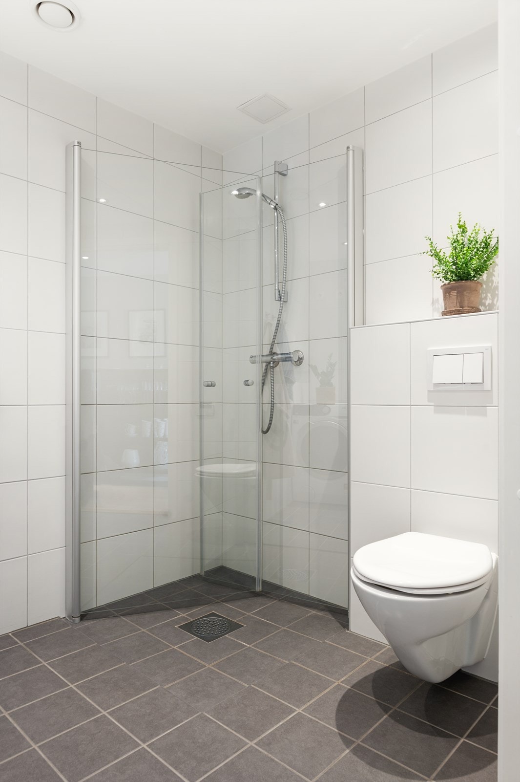 Gulvet er flislagt med varme, veggene er flislagte, og himlingen er malt med downlights som gir en moderne og funksjonell finish. Galleribilde