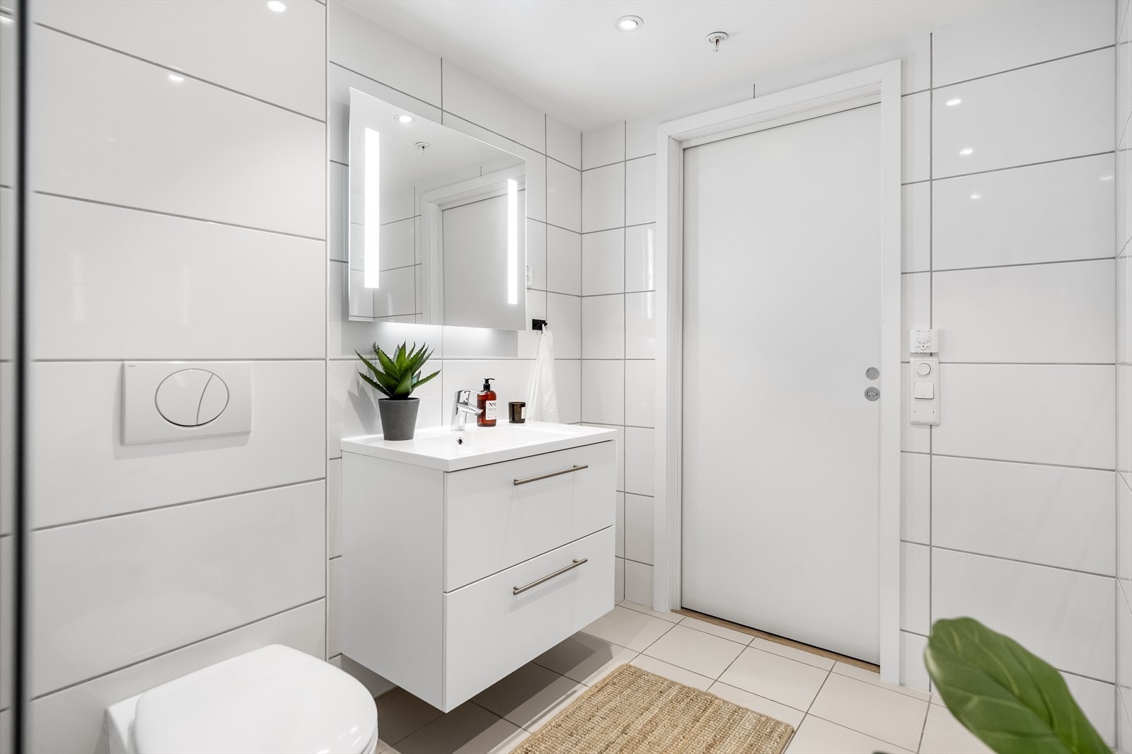 Videre er det speil med integrert belysning, og opplegg for vaskemaskin på badet ved entreen. Galleribilde