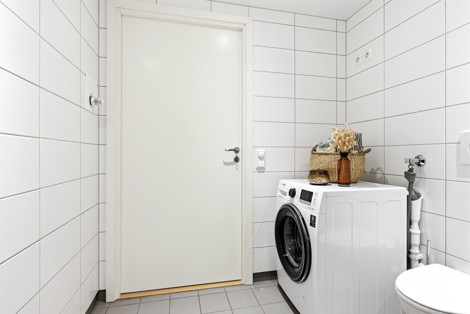 Opplegg for vaskemaskin og tørketrommel, tidløse hvite fliser på veggene. Galleribilde