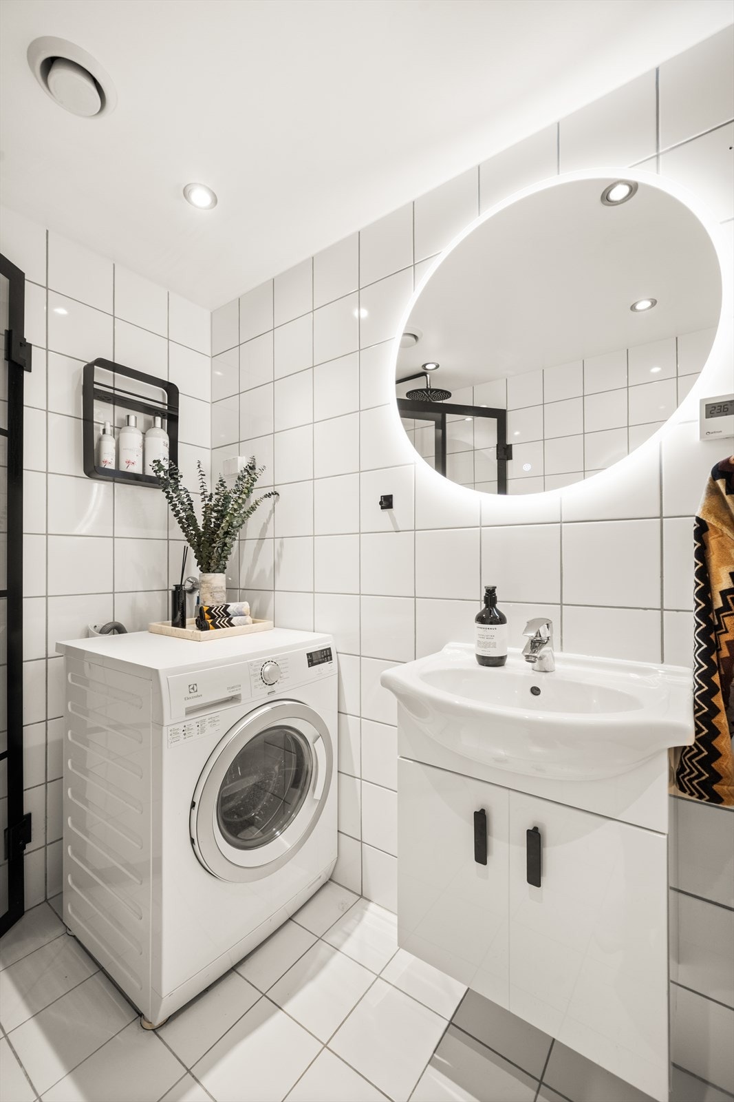 Badet er innredet med vegghengt toalett, dusjhjørne med svingbare glassdører og baderomsinnredning med skap, servant og speil med belysning (2024). Galleribilde