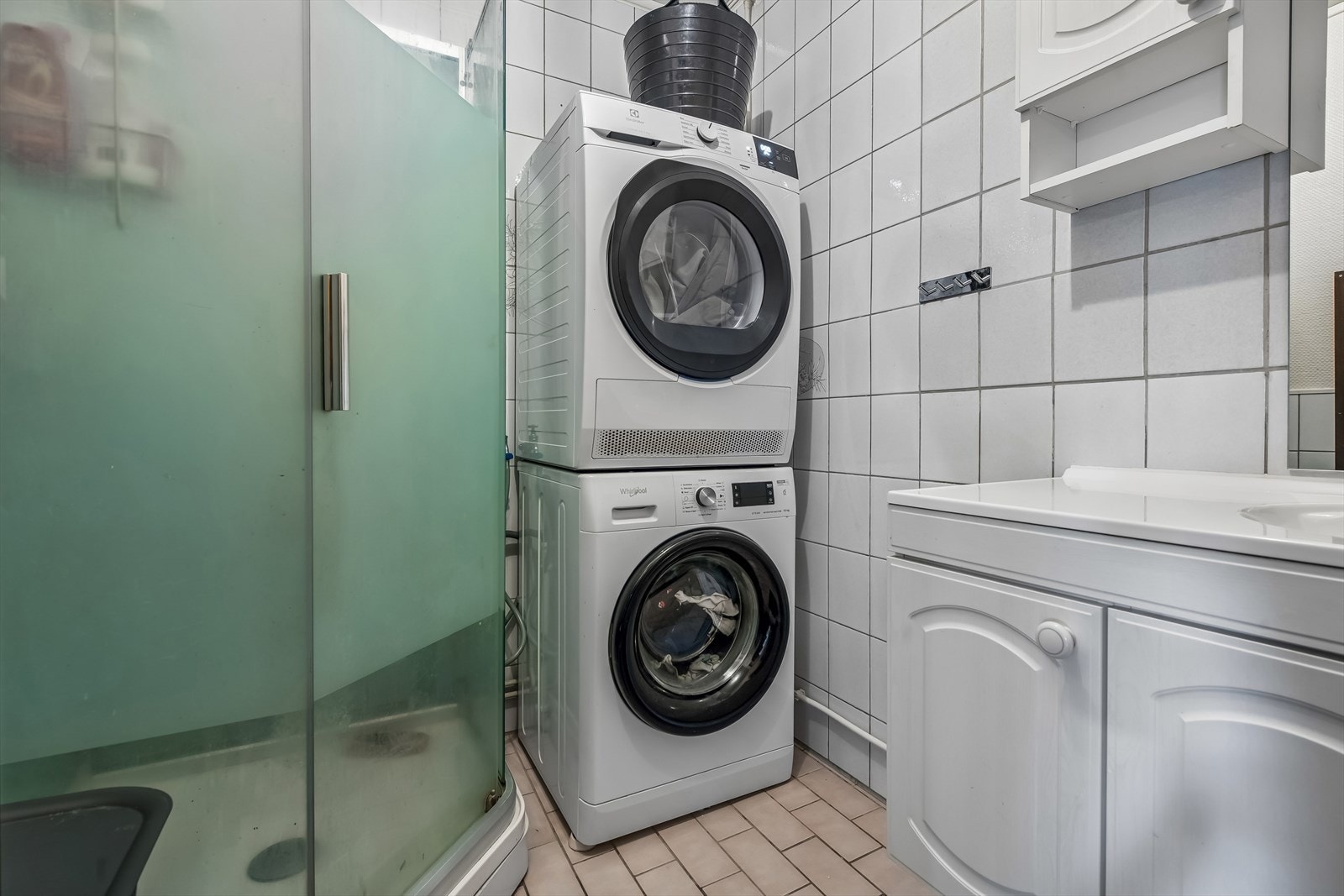 Badet har flislagt gulv med varmekabler, dusjkabinett og opplegg for vaskemaskin. Galleribilde