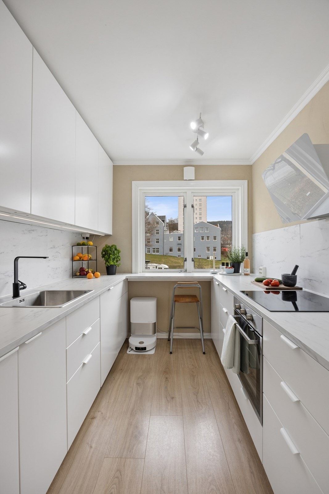 Pent kjøkken med slette lakkerte fronter, laminat benkeplate med plater på bakvegg. Her er det god skap- og benkeplass. Galleribilde