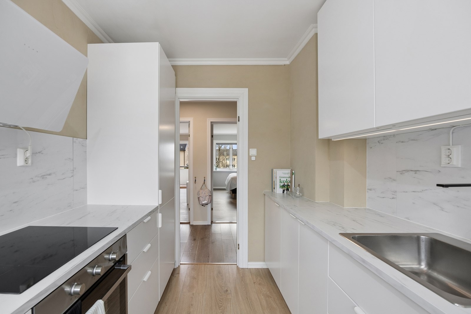 Integrerte hvitevarer som stekeovn, induksjonsplatetopp, oppvaskmaskin samt kombinert kjøle- og fryseskap. Elegant kjøkkenventilator med kullfilter. Alle hvitevarer medfølger handelen. Galleribilde