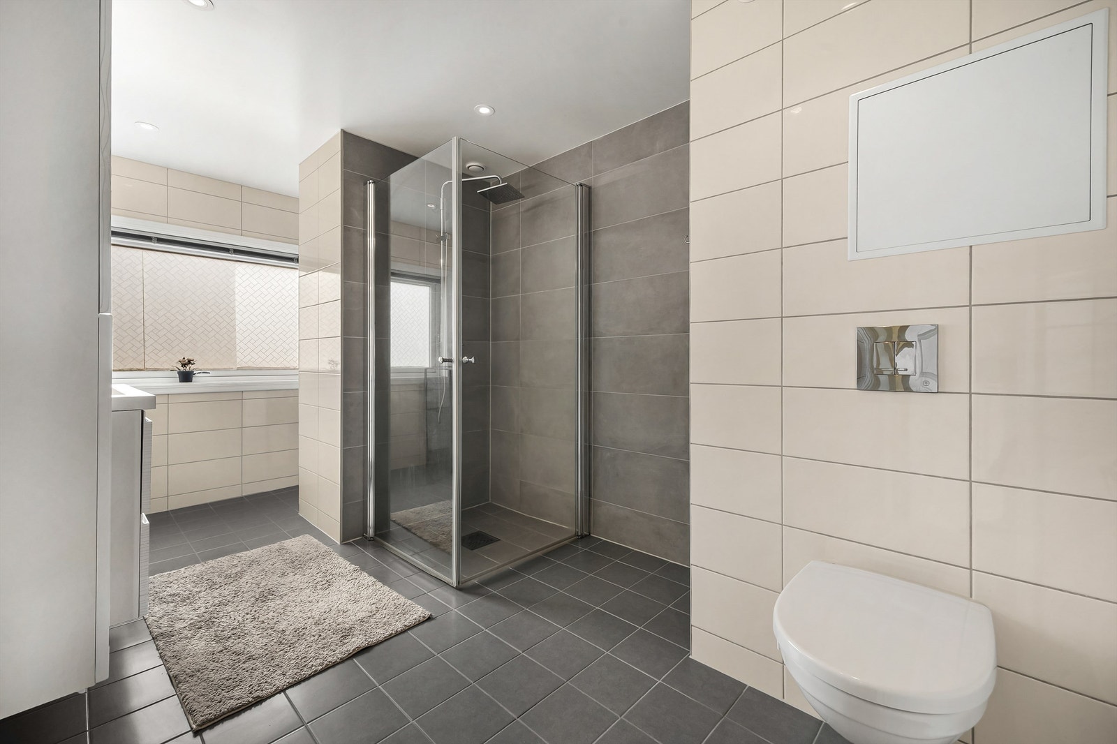 Badet ble oppgradert i 2018 og har flislagt gulv med gulvvarme, vegghengt toalett og dusjhjørne med regnfallsdusj Galleribilde