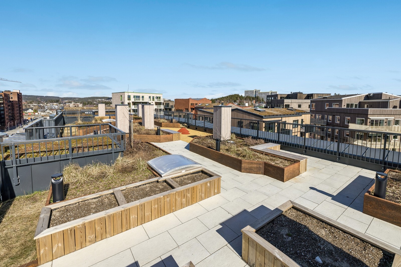 Felles takterrasse med flisalgt dekke, sitteplasser og beplantning. Panoramautsikt over hele området. Galleribilde