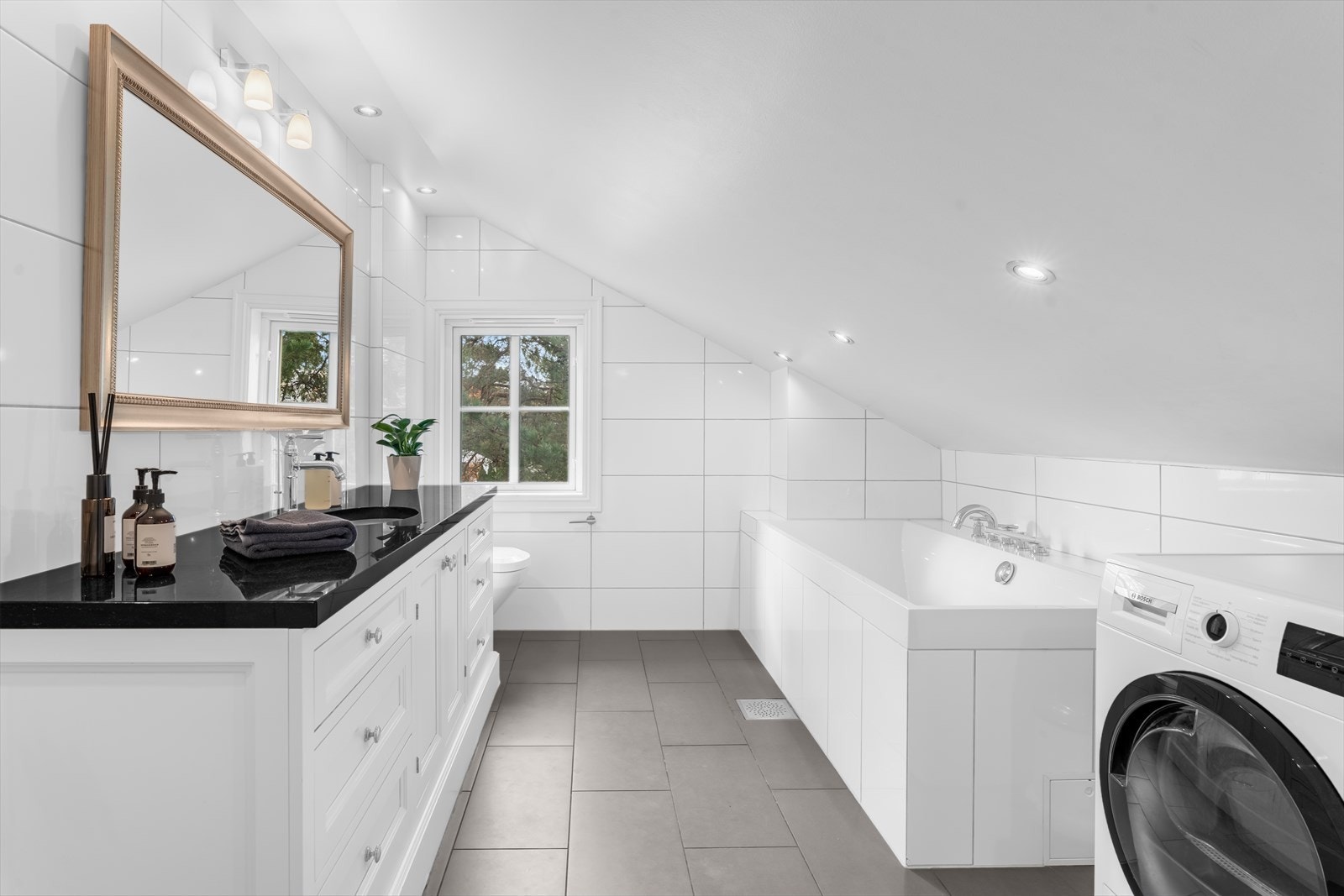 Lyst og lekkert baderom i 2.etg med opplegg for vaskemaskin og tørketrommel. Elegant vask med sort stenplate. Galleribilde