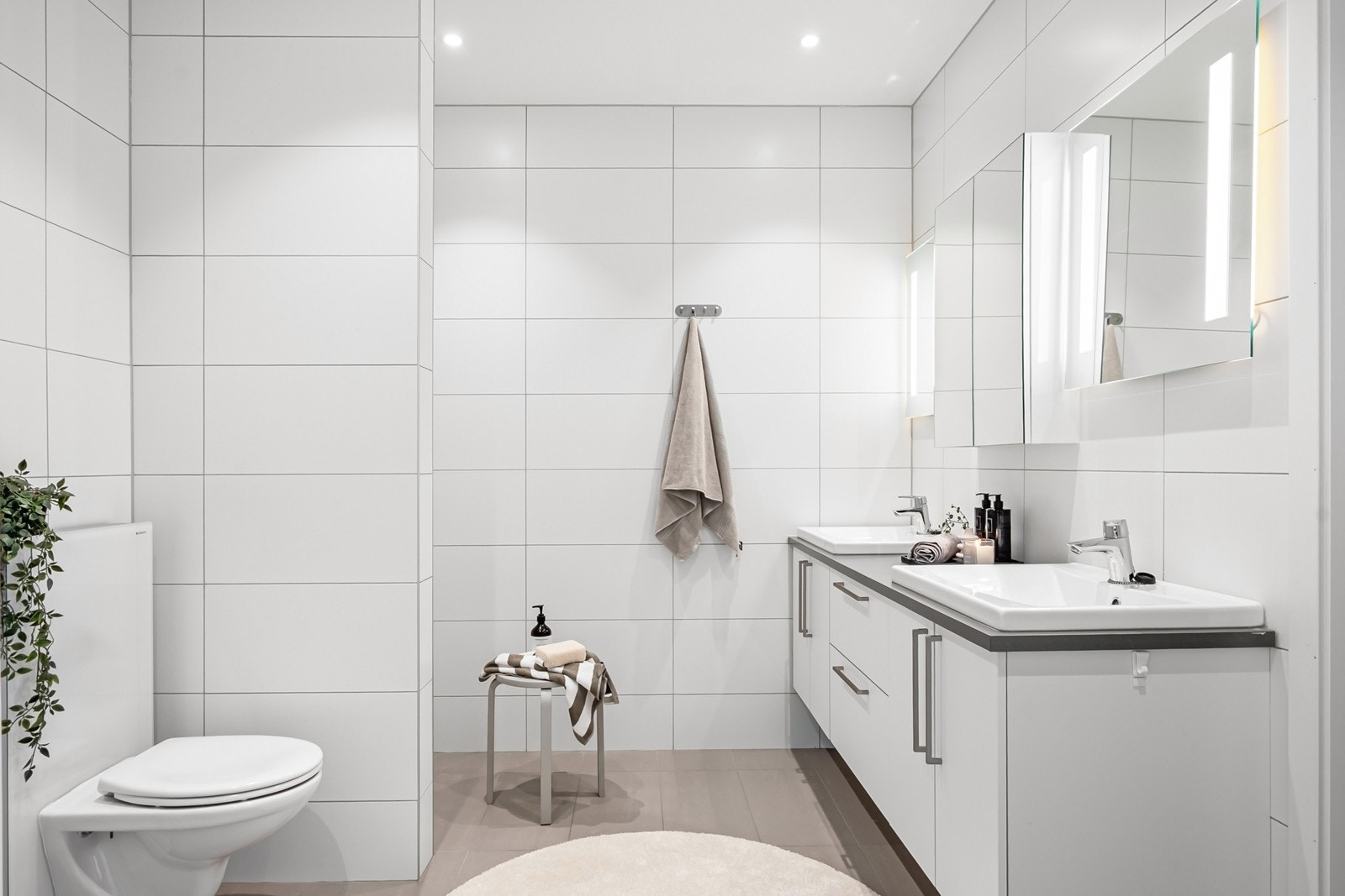 Badet er delikat med flislagte overflater, gulvvarme og downlights, samt innredning fra Sigdal med to servanter, speilskap og speil med lys. Galleribilde