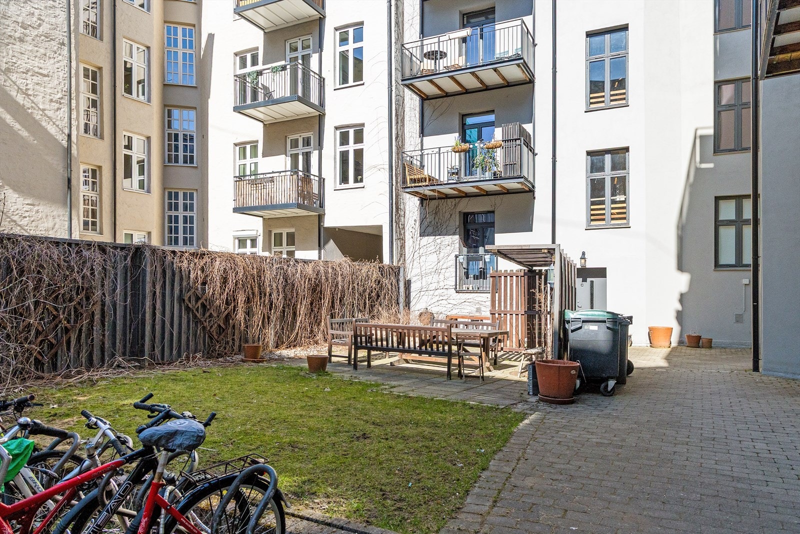 En pen og opparbeidet bakgård med sitteplasser, grønn plen og diverse beplantning. Galleribilde