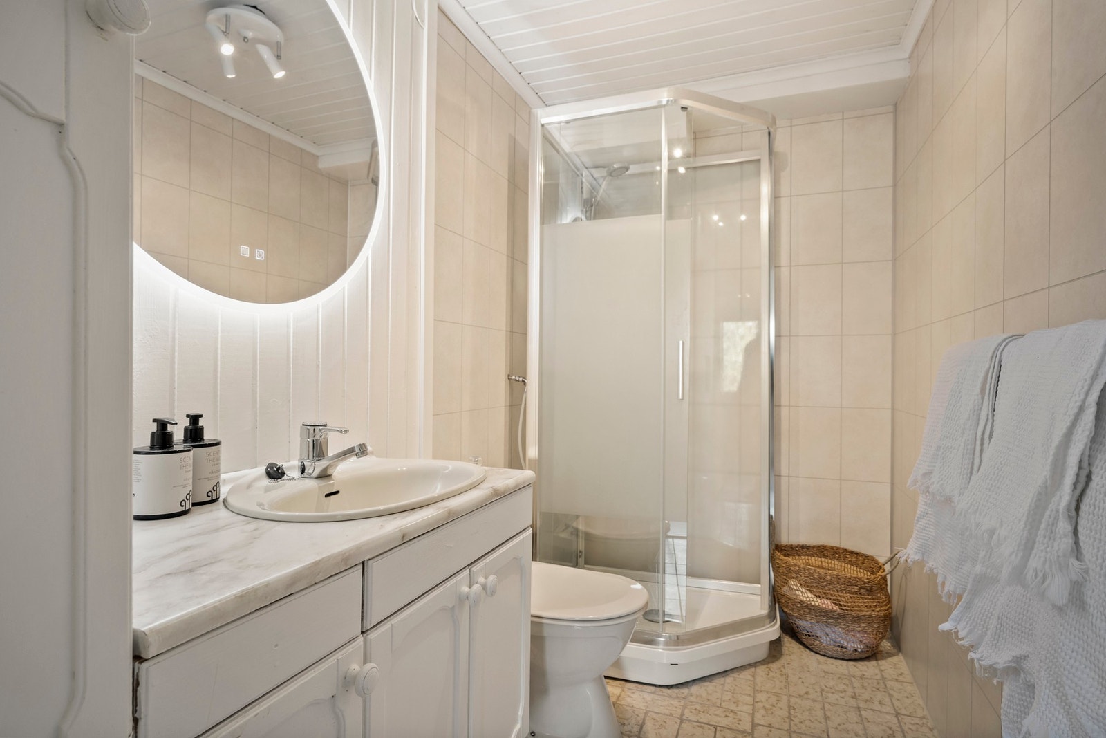 Badet i kjelleren har vegger med panel/tømmer og baderomsplater, mens taket har panel. Galleribilde