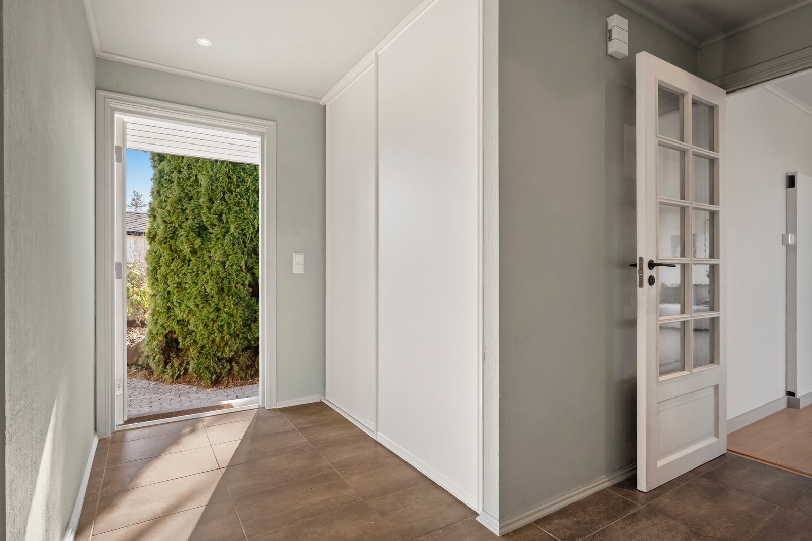 Velkommen inn! Godt med plass for yttertøy og sko i garderobe med hvite skyvedører. Galleribilde