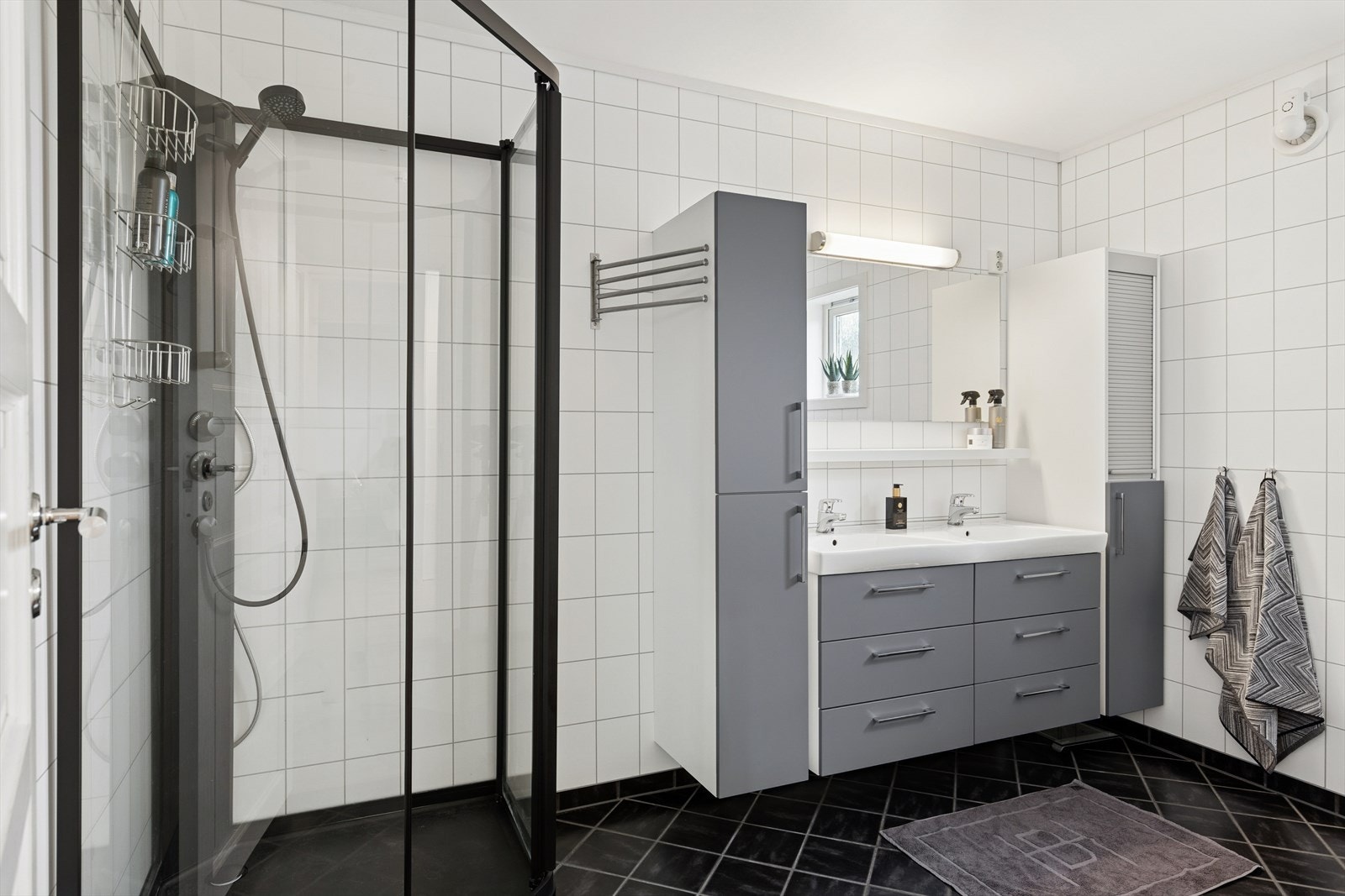 Badet er tilhørende foreldrefløyen med garderobe og soverom. Badet ble totalrenovert i 2010 og er tidløst innredet med mørke fliser på gulv og hvite baderomsplater på vegg. I gulvet har man også varmekabler for ekstra komfort. Galleribilde