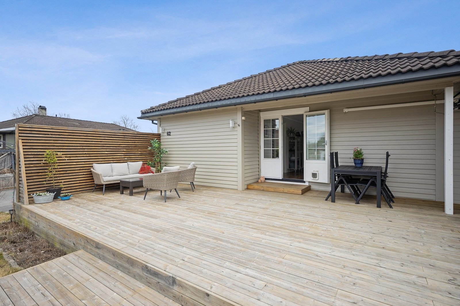 Terrasse med levegg som gir både privatliv og ly for vind. Enkel adkomst til den flotte gressplenen, perfekt for utendørs aktiviteter og avslapning i solen Galleribilde