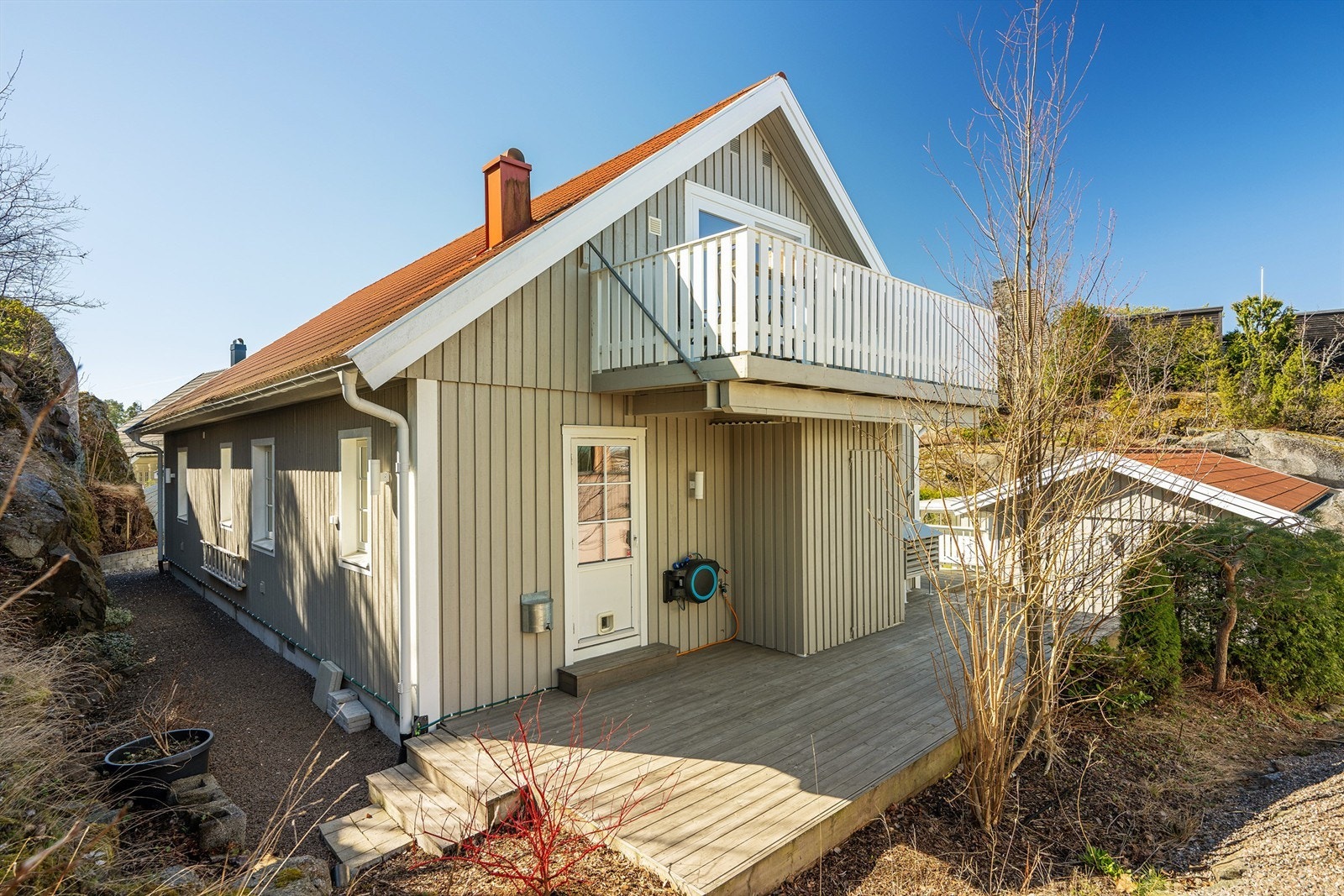 Baksiden av huset med markterrasse og balkongen i loftsetasjen. Galleribilde