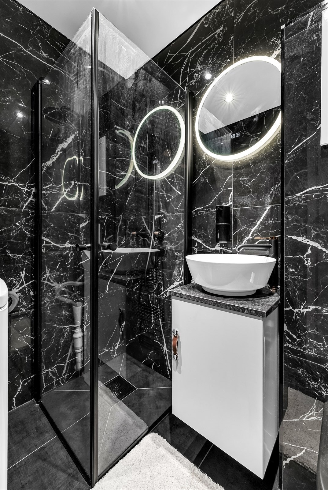 Badet er innredet med servantinnredning, speil med belysning, dusjhjørne og toalett. Galleribilde