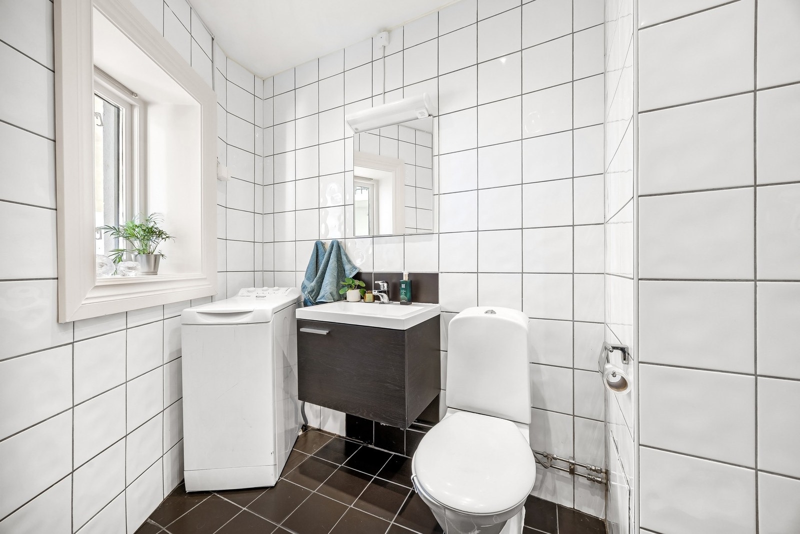 Flislagt bad med varmekabler i gulv og opplegg for vaskemaskin. Galleribilde