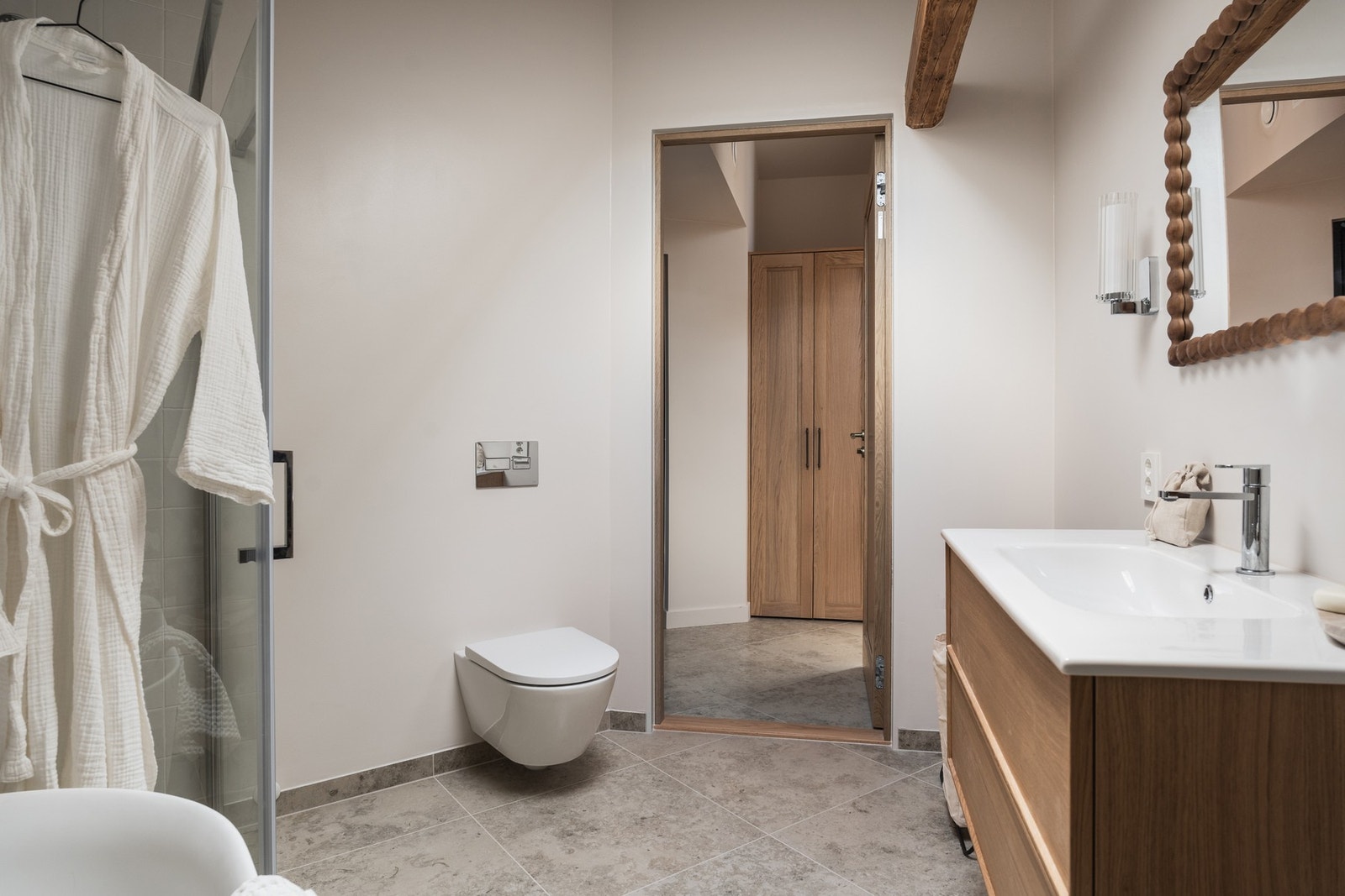 Badet har vegghengt toalett og en romslig dusjnisje. Innredning i eik viderefører den gjennomgående materialpaletten. Galleribilde
