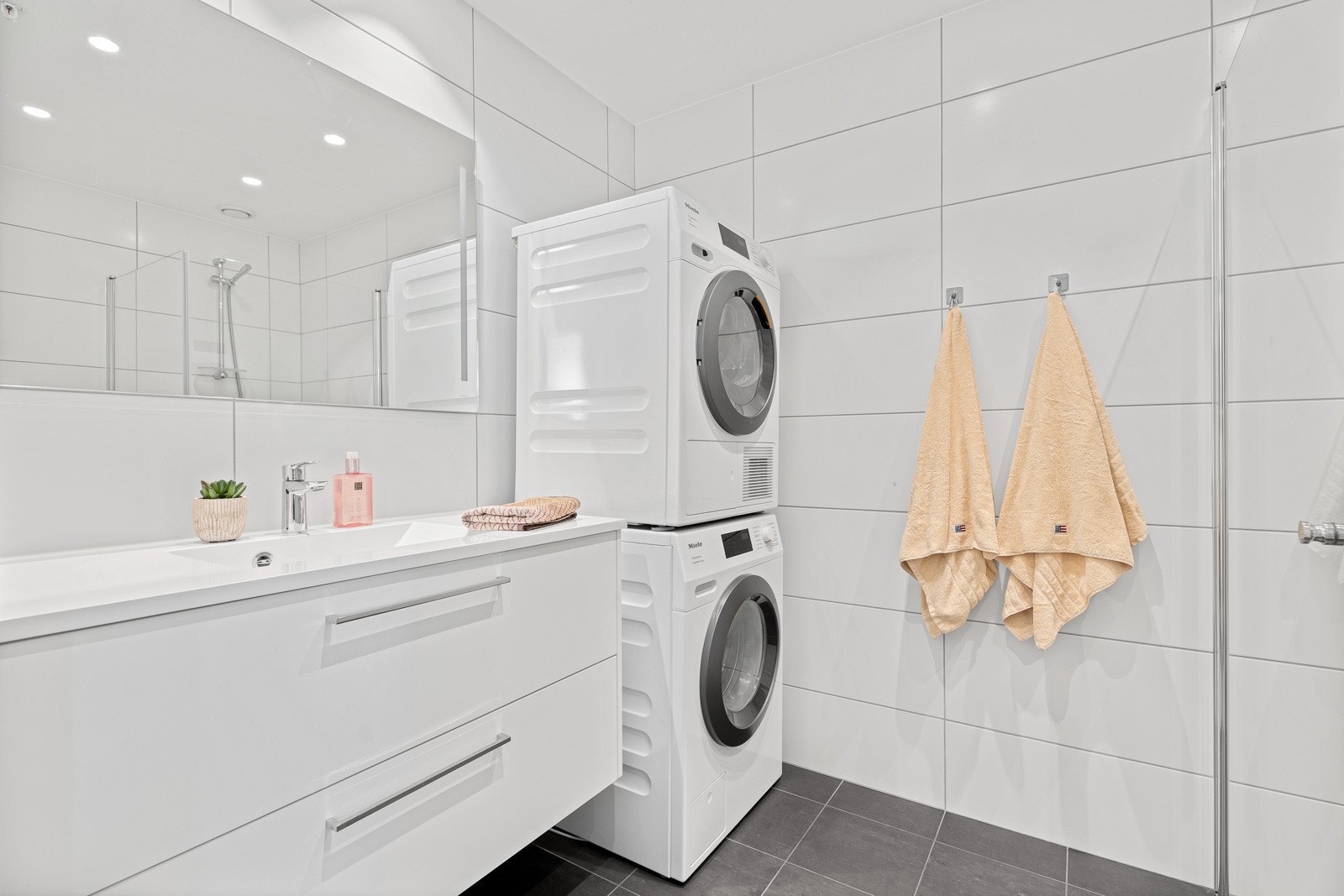 Det største badet ligger i suite med hovedsoverommet og har opplegg for vaskesøyle. Rommene er utført med samme type fliser og innredning, noe som gir en fin helhet. Galleribilde