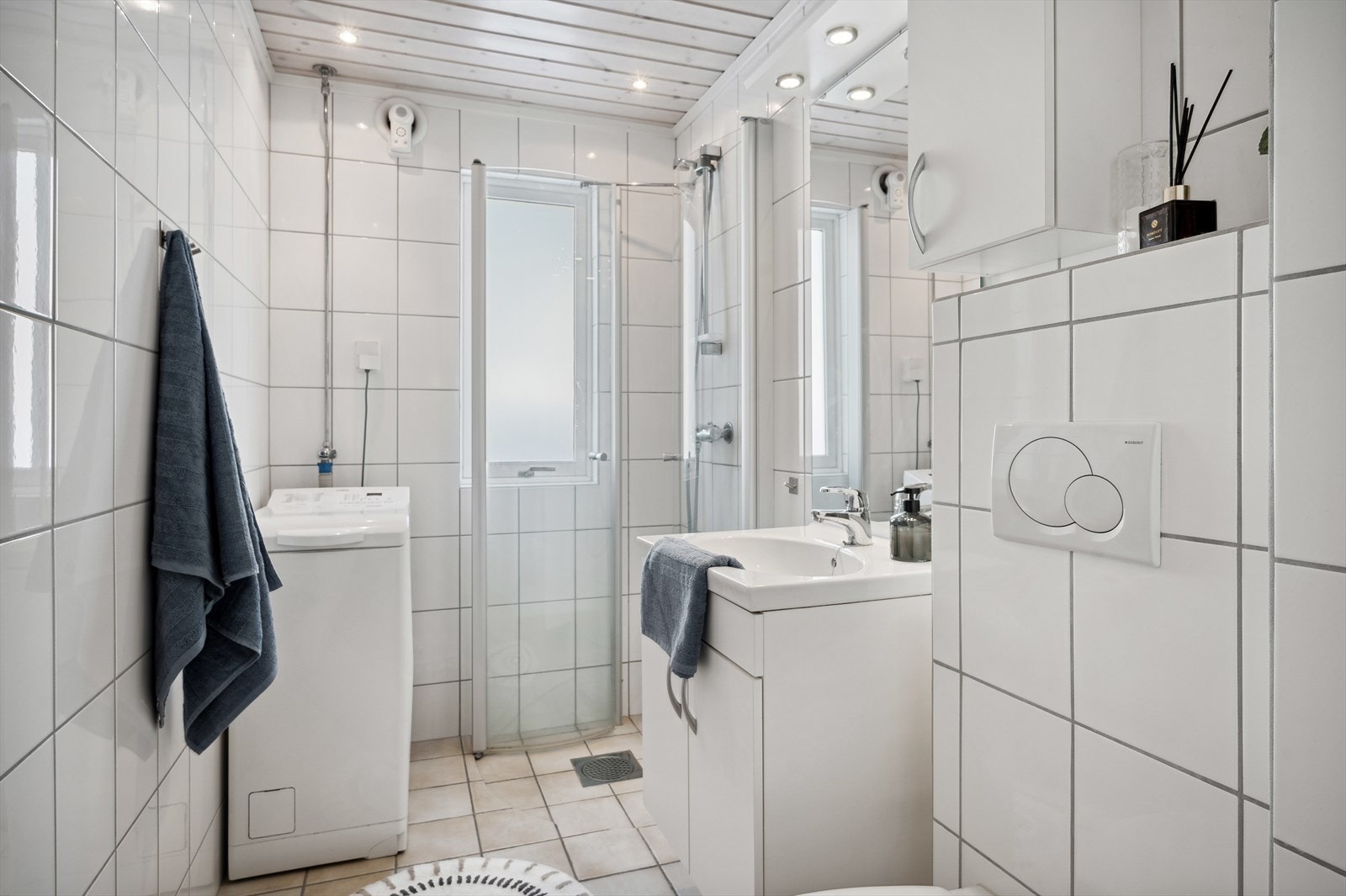Bad/WC med dusjhjørne, vaskemaskin og vegghengt WC Galleribilde