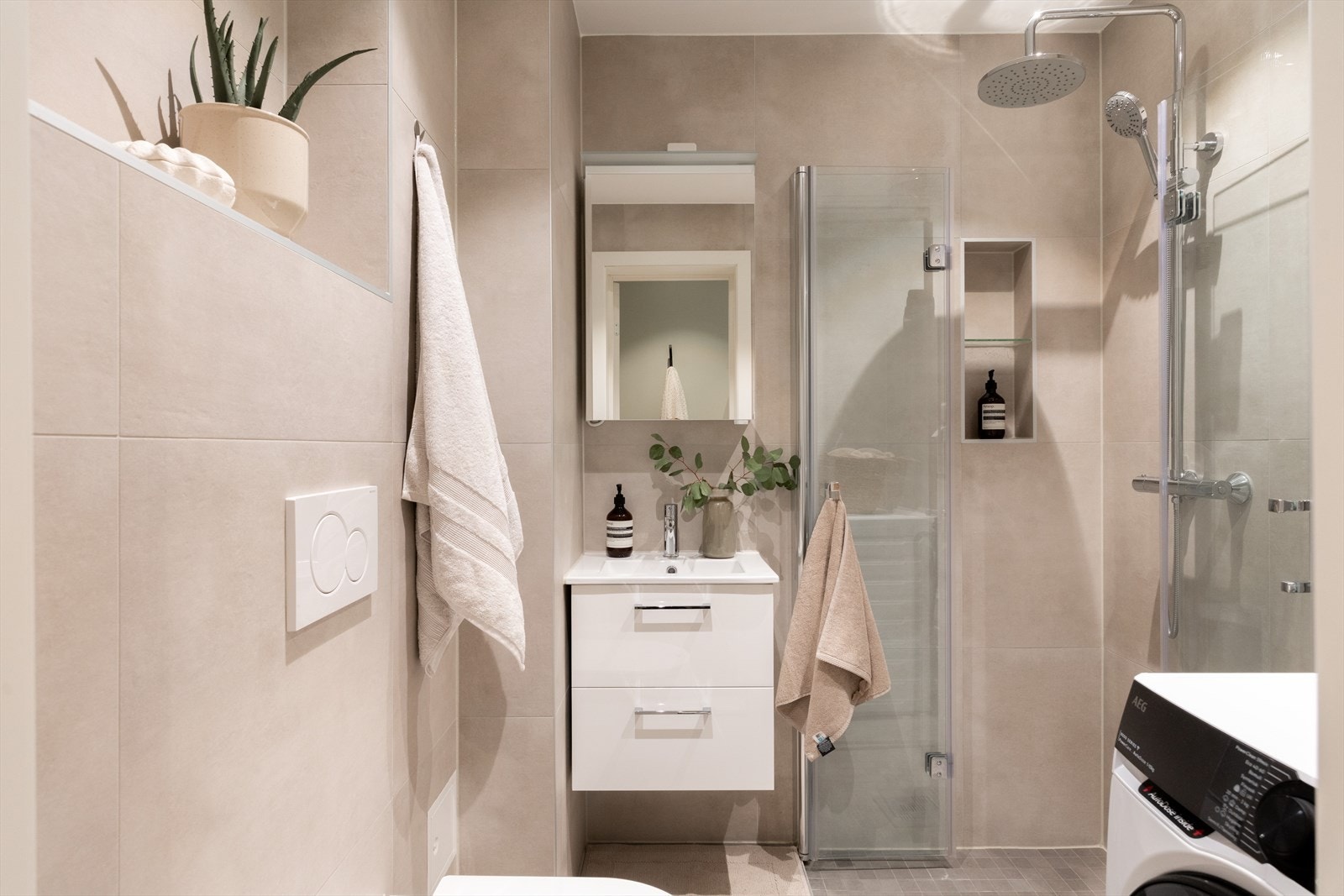 Badet er innredet med vegghengt toalett med soft close-sete, speil, servant med innredning og Merkur servantkran mini, og opplegg for vaskemaskin og tørketrommel. Galleribilde