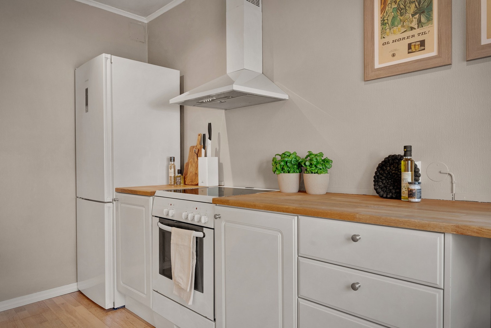 Kjøkken med profilerte hvite fronter med innslag av glassfelt, benkeplate i heltre eik og
vaskekum i stål. Galleribilde