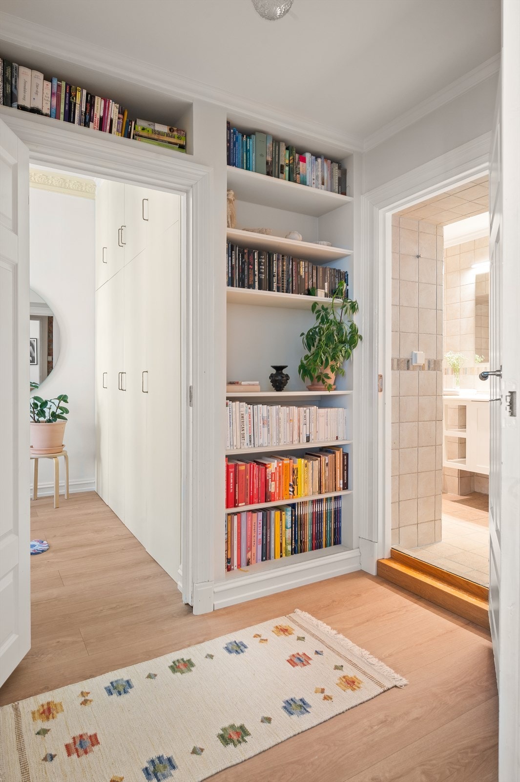 Plassbygde bokhyller gir både karakter og praktisk oppbevaring i passasjen mot bad og soverom. Galleribilde