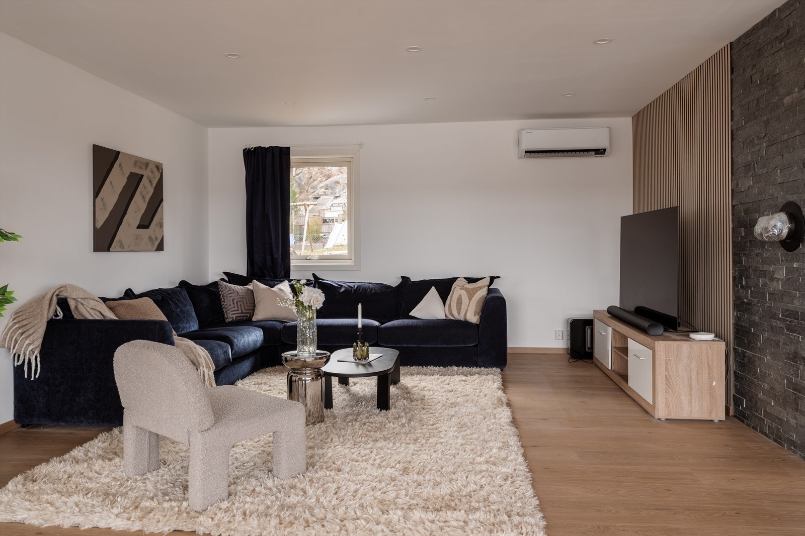 En moderne spilevegg og en fondvegg skaper en stilren ramme for TV-sonen. Galleribilde