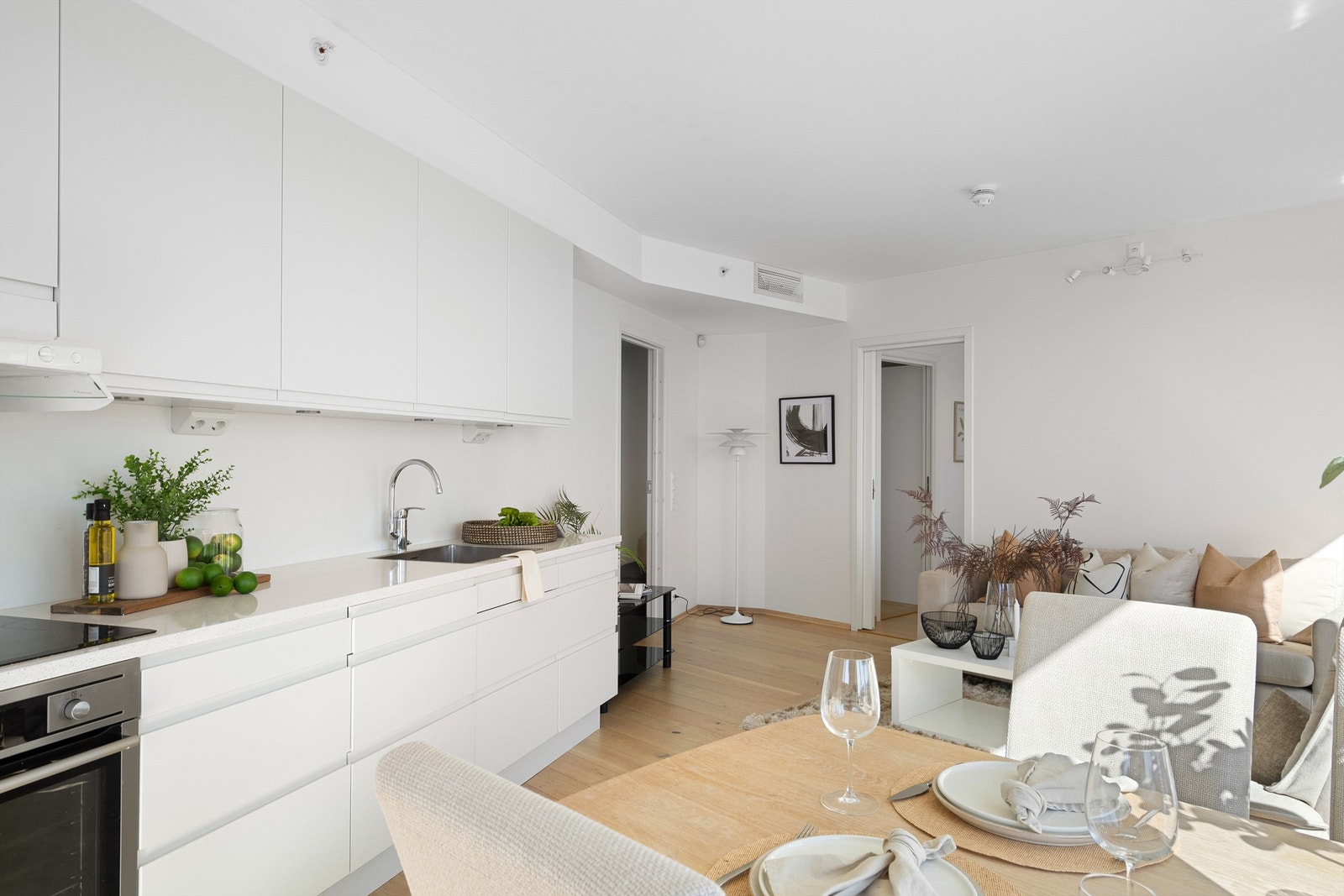 Kjøkkenet er i moderne og fint design med fronter hvitt. Lys benkeplate. Kjøkkeninnredning er fra HTH og det er integrerte hvitevarer, spotter under overskap og bra med benke - og skapplass. Ved kjøkkenet er plass til spisebord. Galleribilde