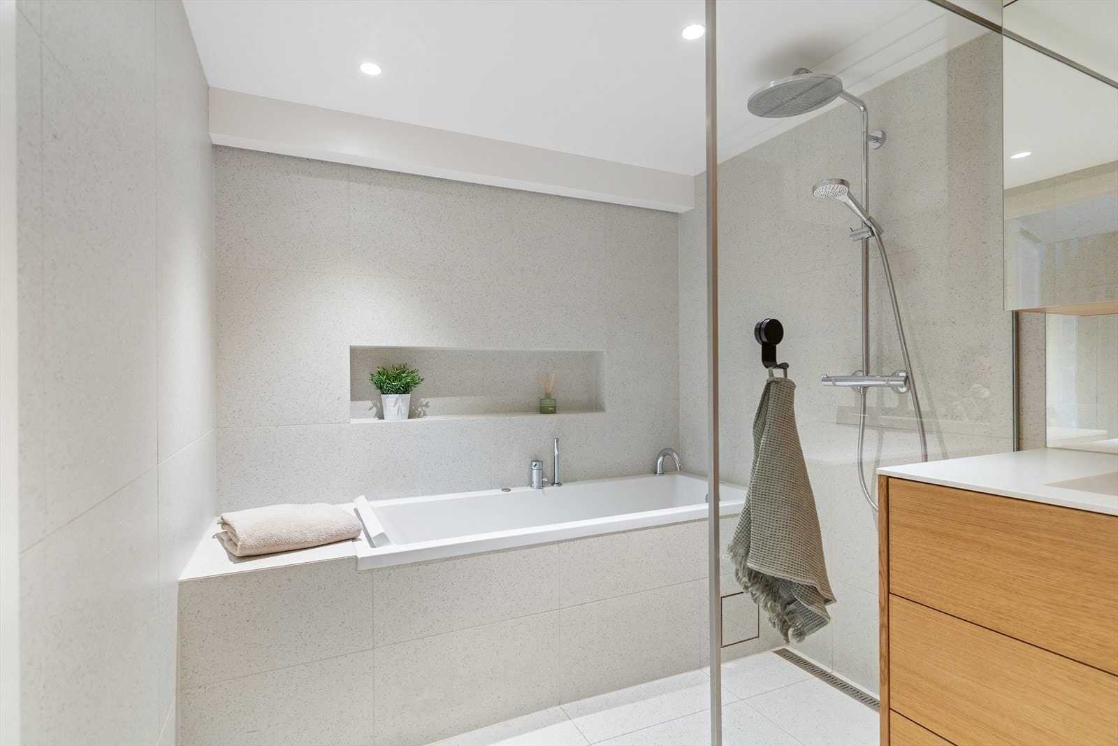 Badet er innredet med både badekar og separat dusjsone med glassvegger. En nisje ved badekaret gir praktisk oppbevaring. Galleribilde