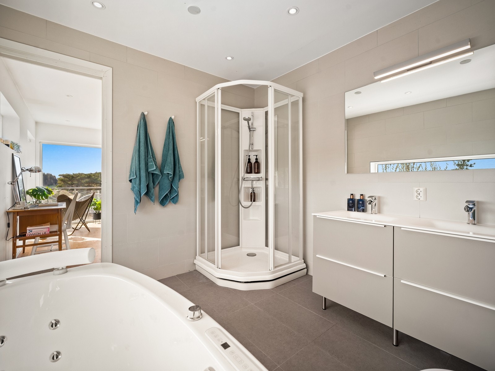 Badet er i direkte tilknytning til hovedsoverom. Himlingen har malte plater med innfelte downlights. Vegger og gulv er flislagt, og gulvet har elektrisk gulvvarme for ekstra komfort. Galleribilde
