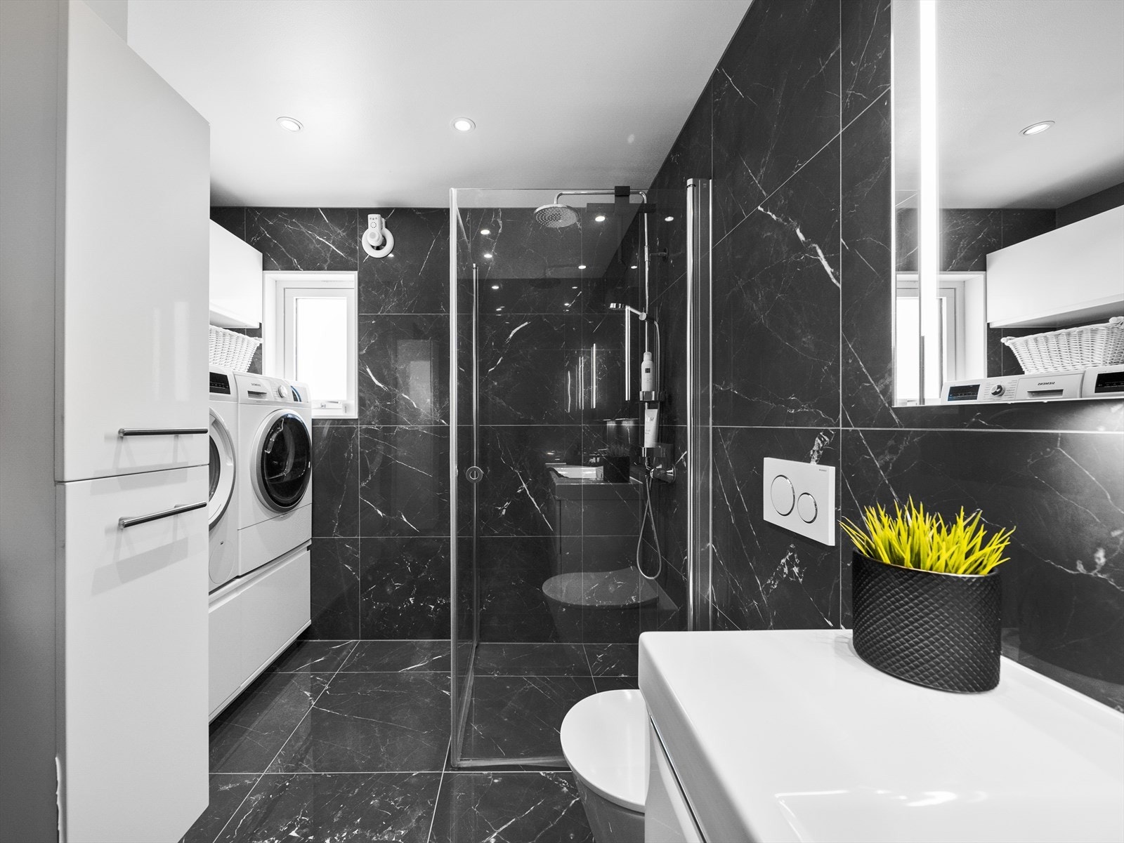 Badet er innredet med nedfelt servant, veggmontert toalett, dusjvegger/hjørne, opplegg for vaskemaskin/tørketrommel og speil m/belysning. Galleribilde