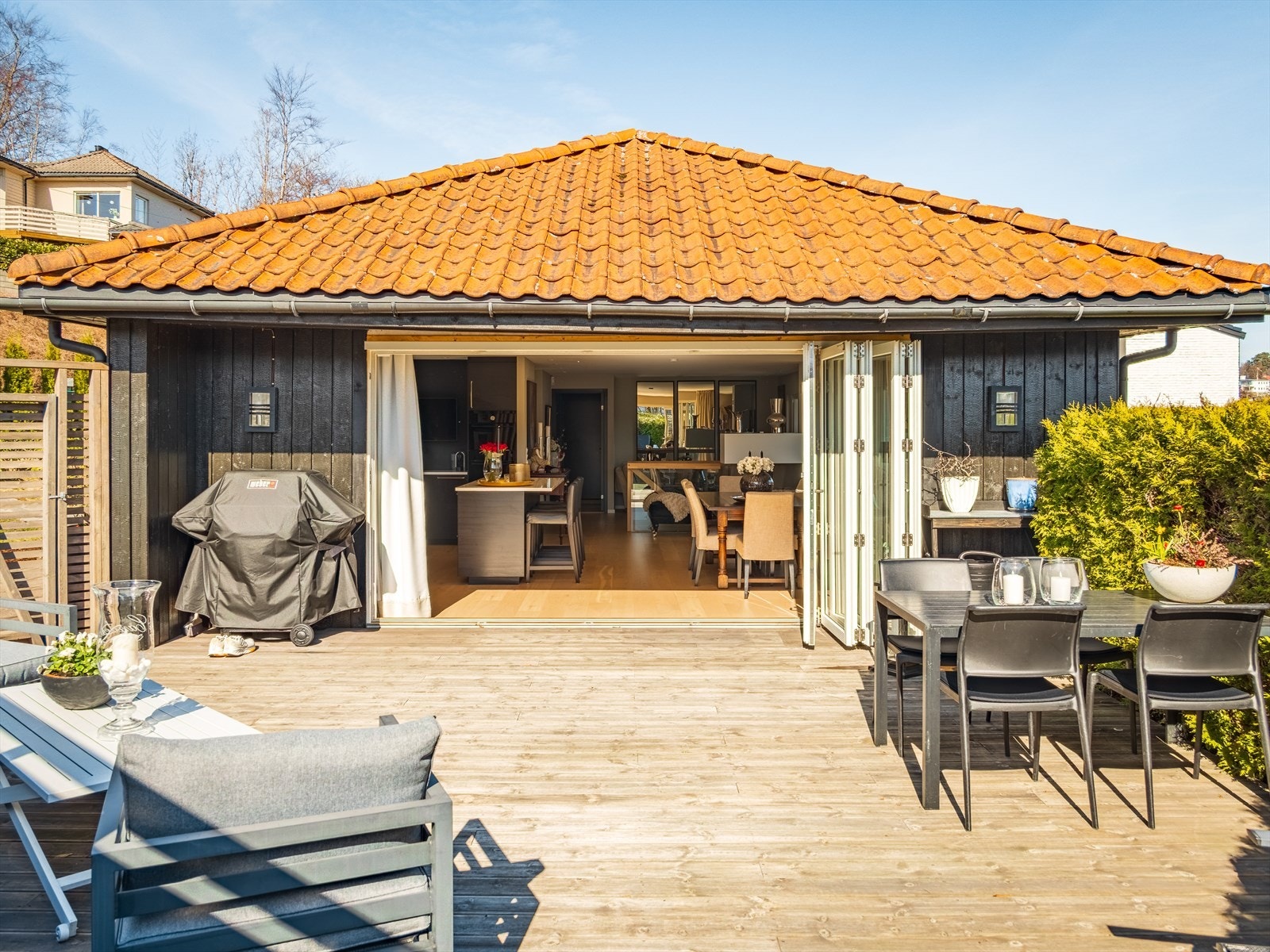 De brede foldedørene åpner opp hele veggen og skaper en sømløs overgang mellom uteplassen og den åpne stue- og kjøkkenløsningen - perfekt for sosiale sammenkomster på fine dager. Galleribilde