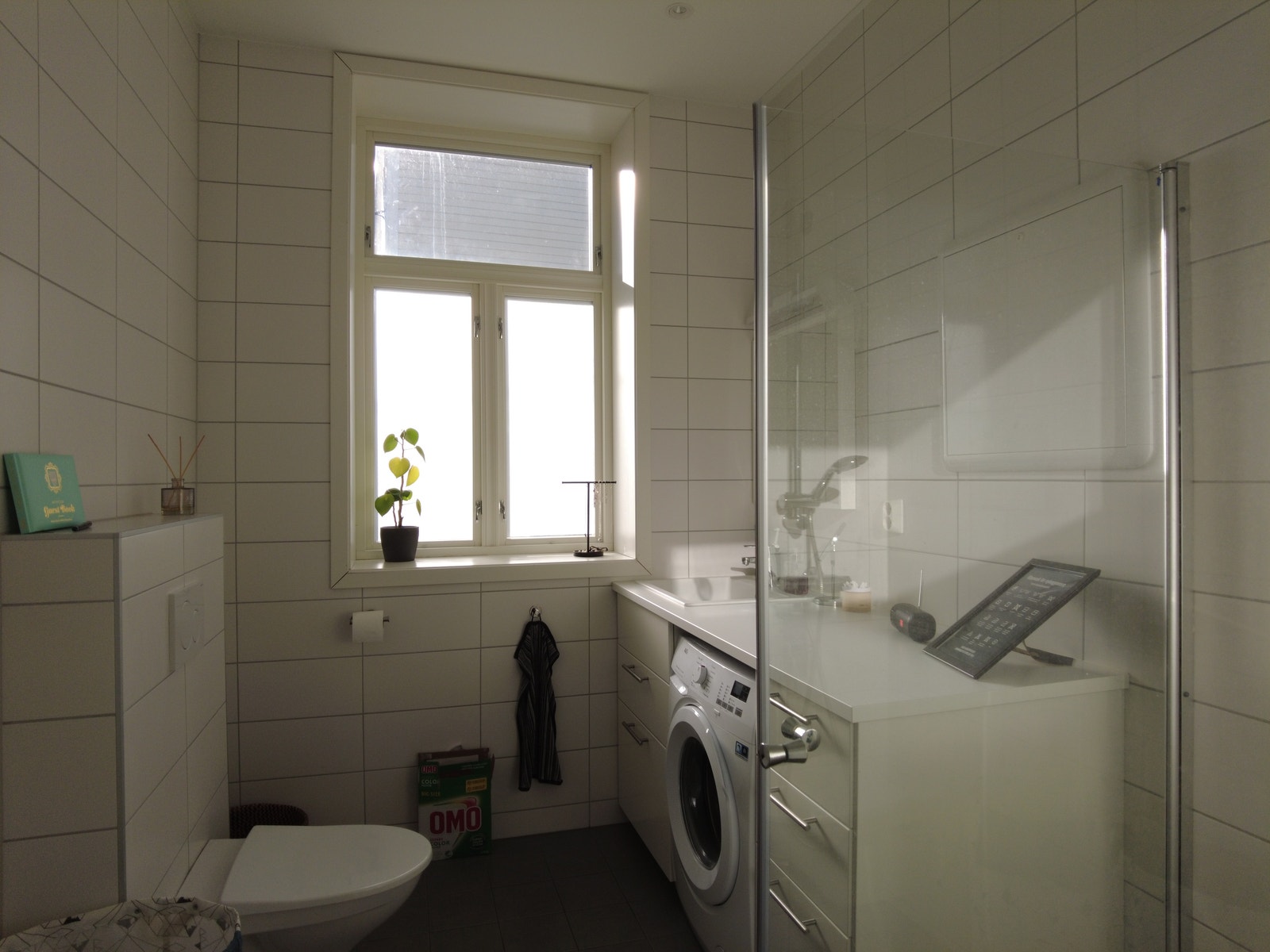Bad. Flislagte gulv og vegger. Varme i gulv, vegghengt wc, dusjhjørnet, servant med underskap, speil og vaskemaskin. Galleribilde