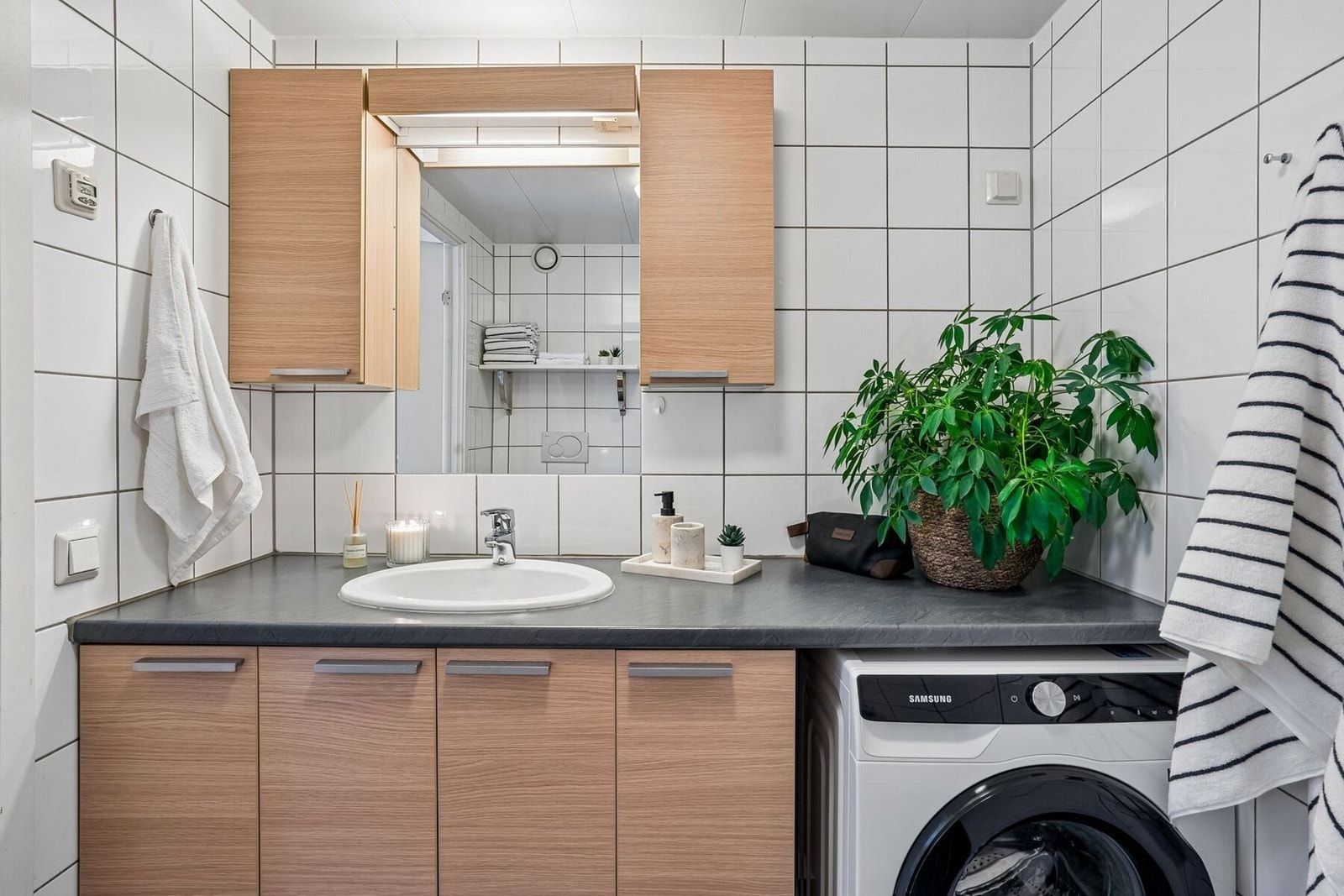 Badet er praktisk utformet med opplegg for vaskemaskin og forlenget benkeplate som gir god arbeids- og oppbevaringsplass. Galleribilde