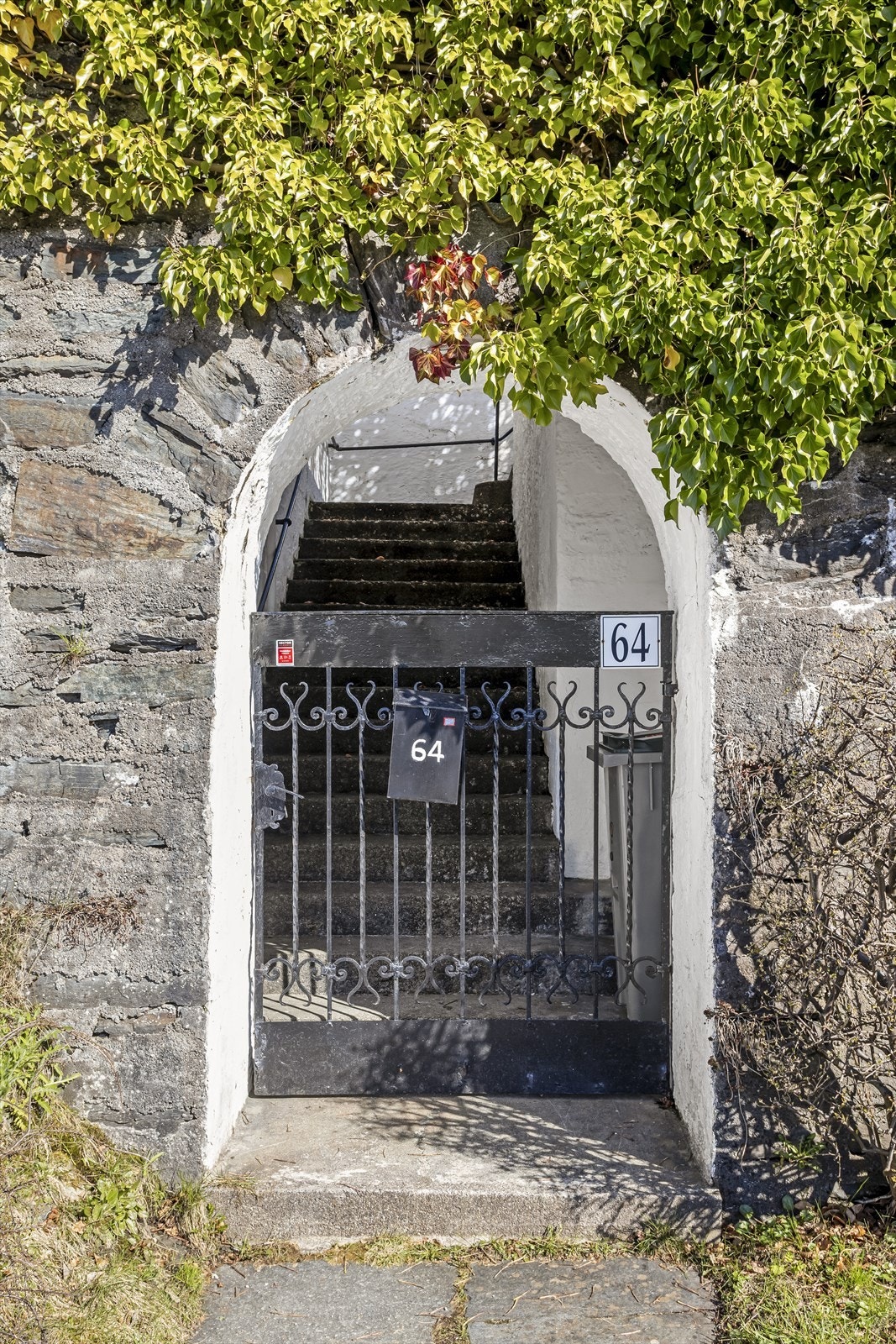 En sjarmerende portal i natursteinsmuren leder fra Fjellveien og opp til eiendommen. Galleribilde