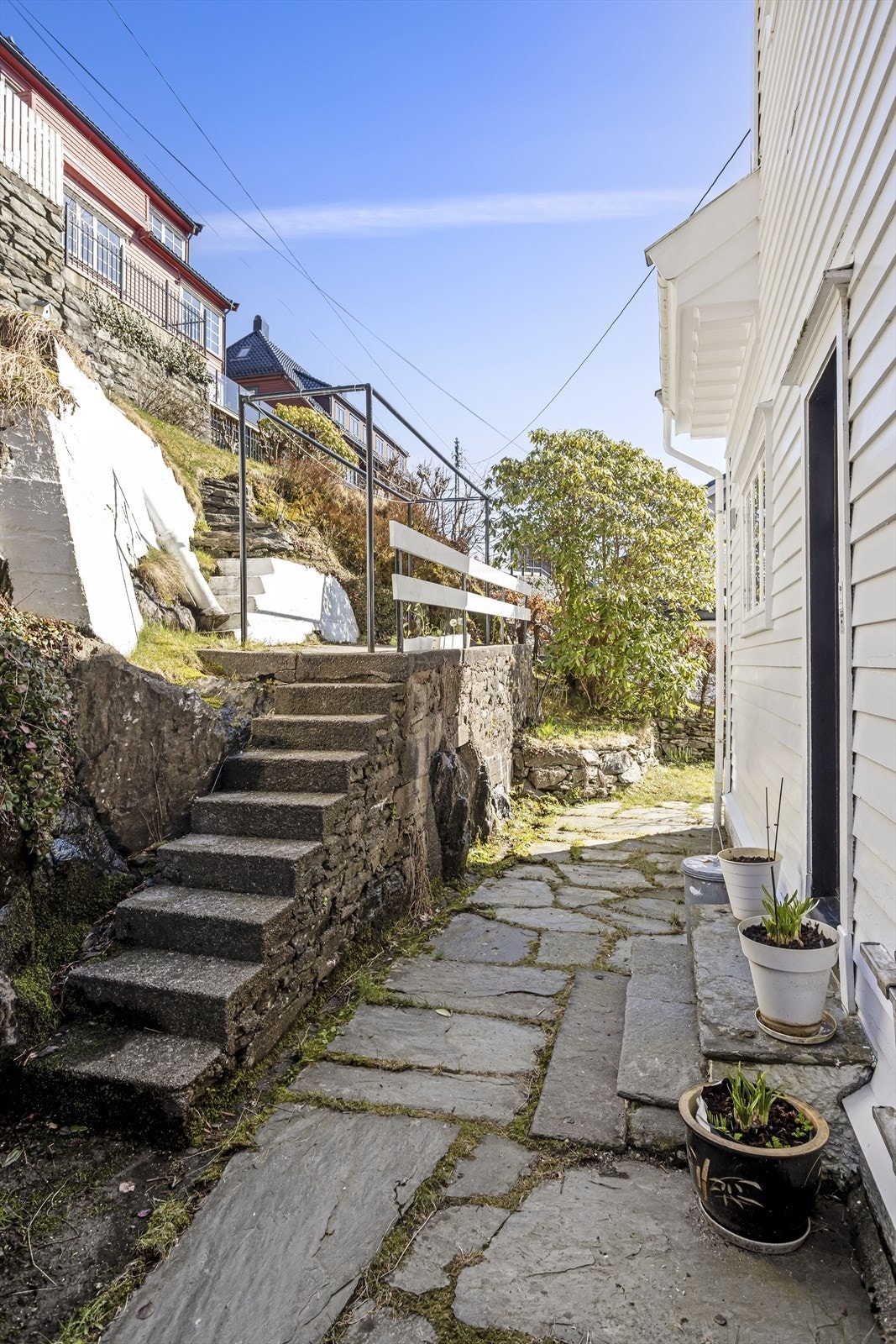 Støpte trapper og hellelagte stier gir adkomst rundt boligen og opp i det skrånende terrenget. Galleribilde