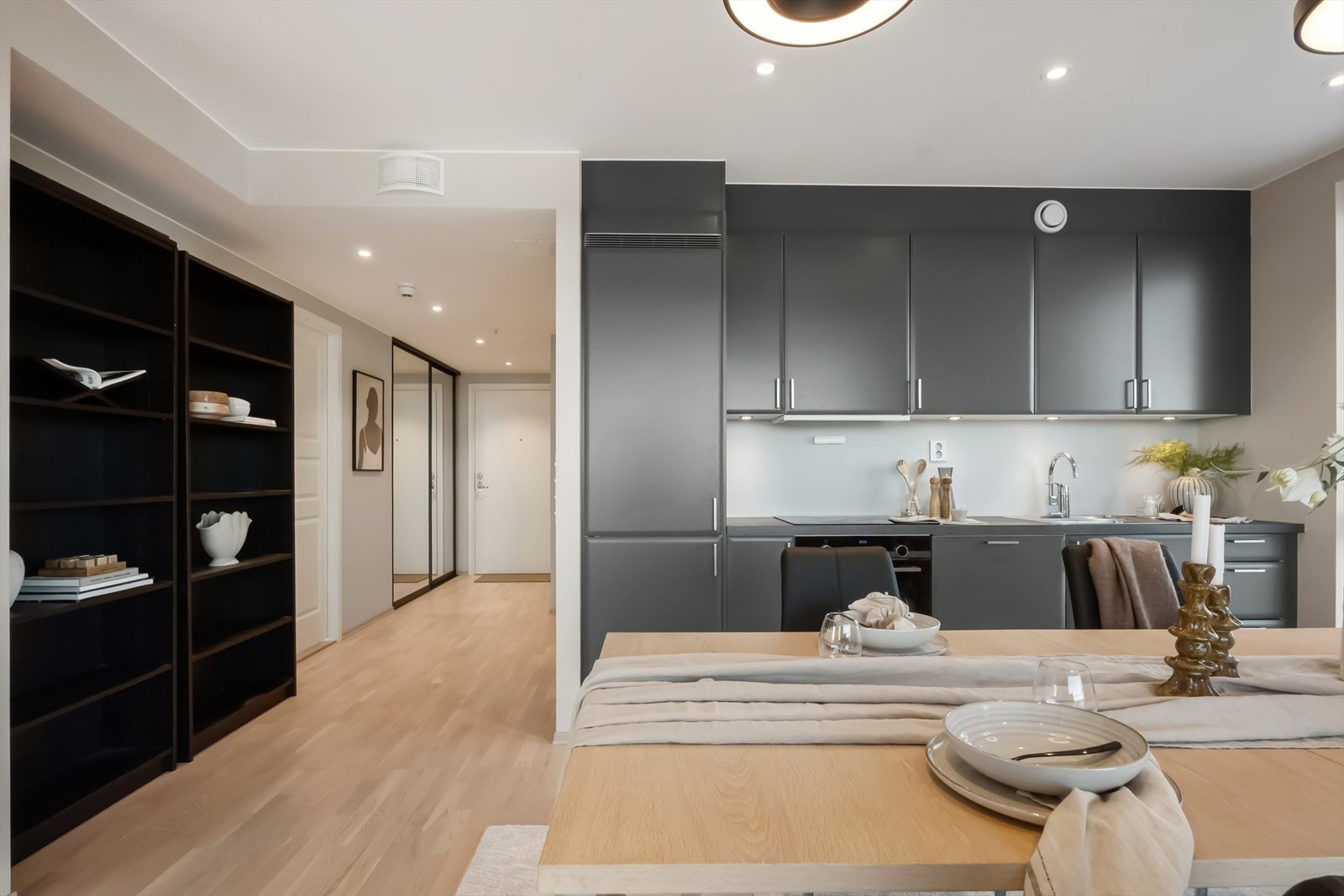 Kjøkkenet fra 2021 fremstår moderne og stilrent, med mørke, glatte fronter og en mørk laminert benkeplate med nedfelt vask i rustfritt stål. Galleribilde