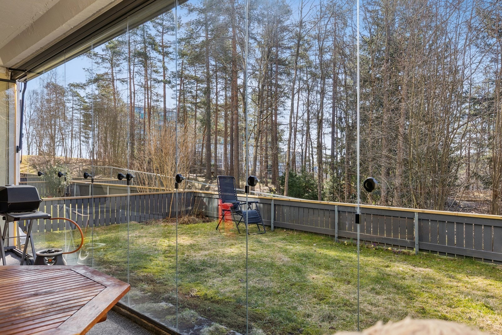 En lun og skjermet uteplass med innglasset terrasse som vender ut mot en grønn hage - perfekt for avslapning og hyggelige stunder utendørs Galleribilde