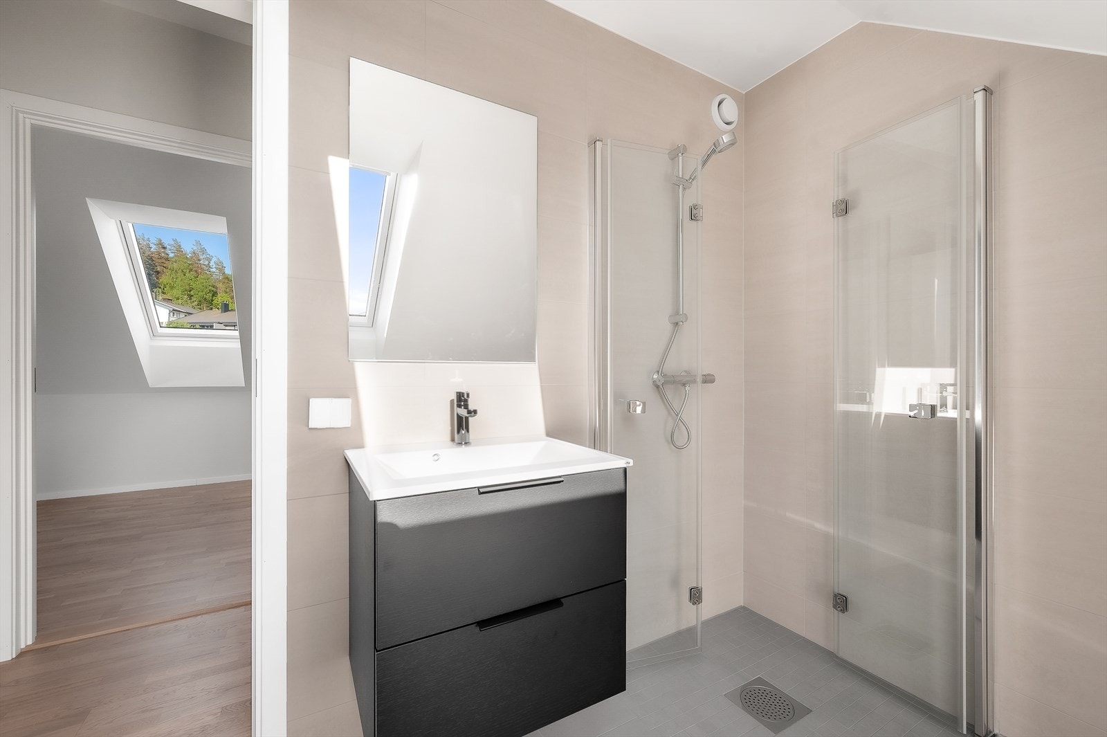 Badet er innredet med vegghengt toalett, en moderne baderomsinnredning fra JKE Billingstad og dusjhjørne med innfellbare foldedører i glass Galleribilde