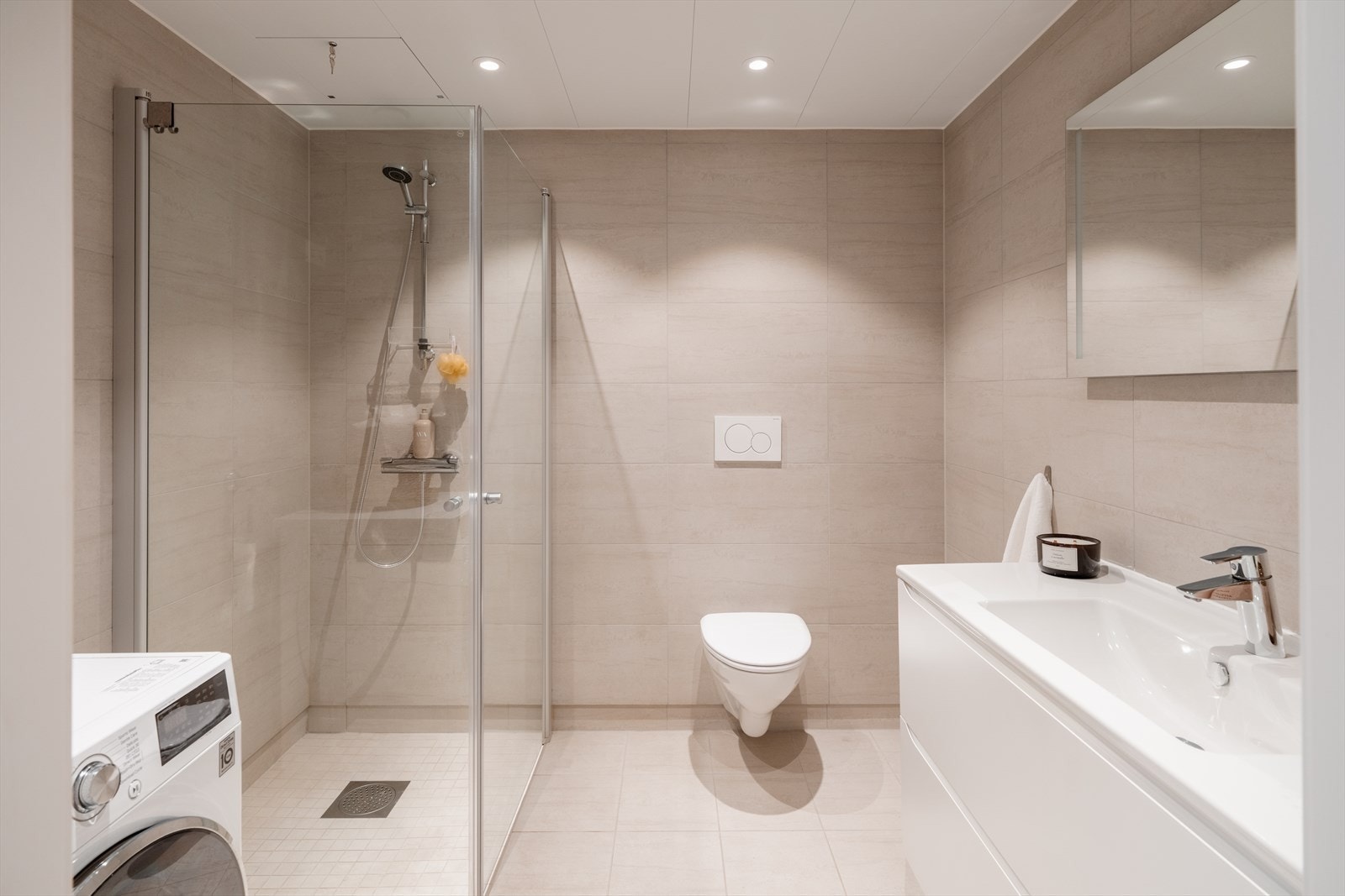 Leiligheten har et pent og moderne bad med behagelig atmosfære. Her er det store, sandfargede fliser på veggene, downlights i himlingen og lyse fliser på gulv med elektrisk gulvvarme. Galleribilde