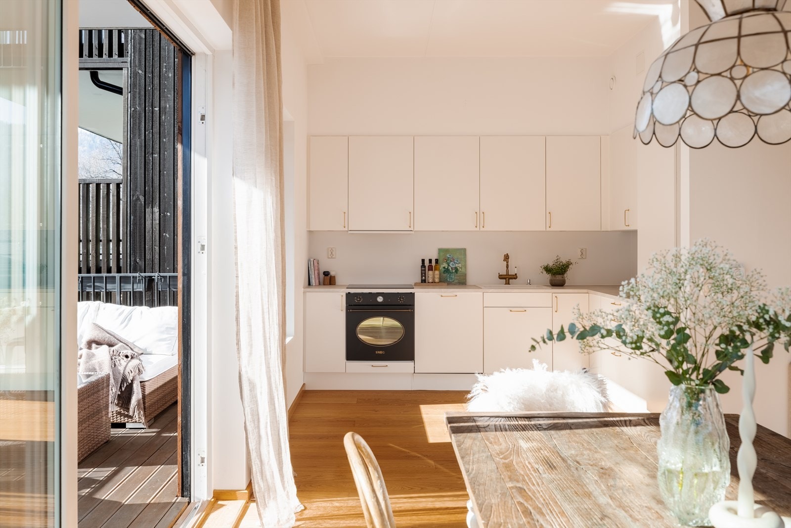 Kjøkkenet har et stilrent og arealeffektivt design - praktisk plassert i en L-form i en egen del av det åpne allrommet. Galleribilde