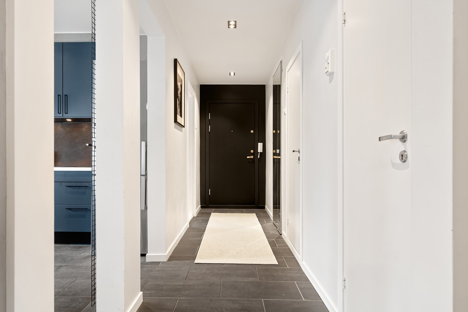 Romslig entré med sorte gulvfliser i 30 x 60 cm, lysmalte vegger og innfelte downlights som gir et svært godt førsteinntrykk. Galleribilde