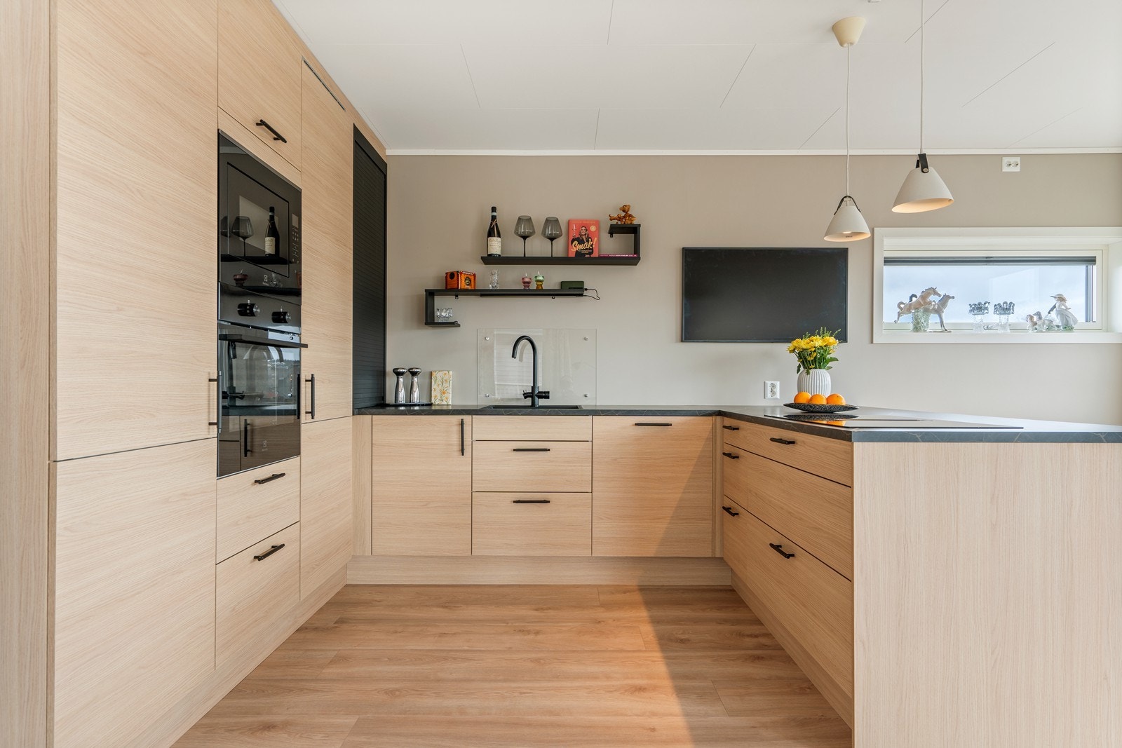 Flott og moderne kjøkken utført med slette fronter og benkeplate av laminat med nedfelt vask. Galleribilde