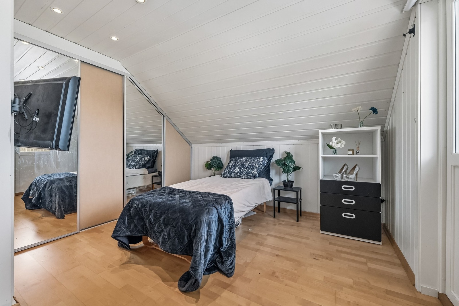 Rommet har laminatgulv, malte panelvegger og sjarmerende skråtak, samt plassbygget seng og integrert skyvedørsgarderobe. Galleribilde