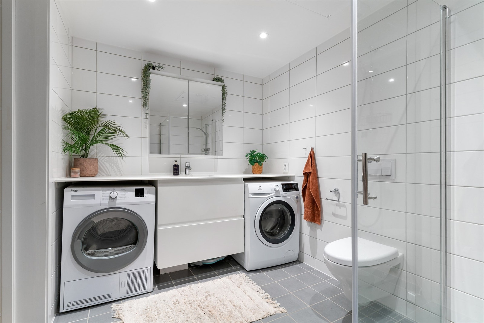 Badet er utstyrt med vegghengt toalett og dusjhjørne med innfellbare glassdører. Galleribilde