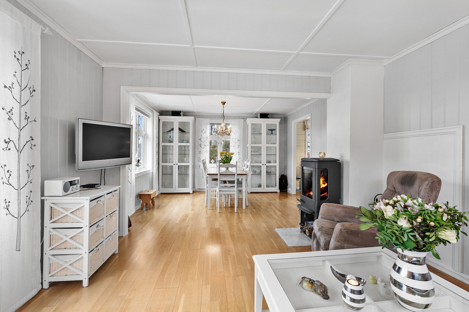 Midt i rommet står en vedovn som fungerer som et naturlig samlingspunkt. Galleribilde