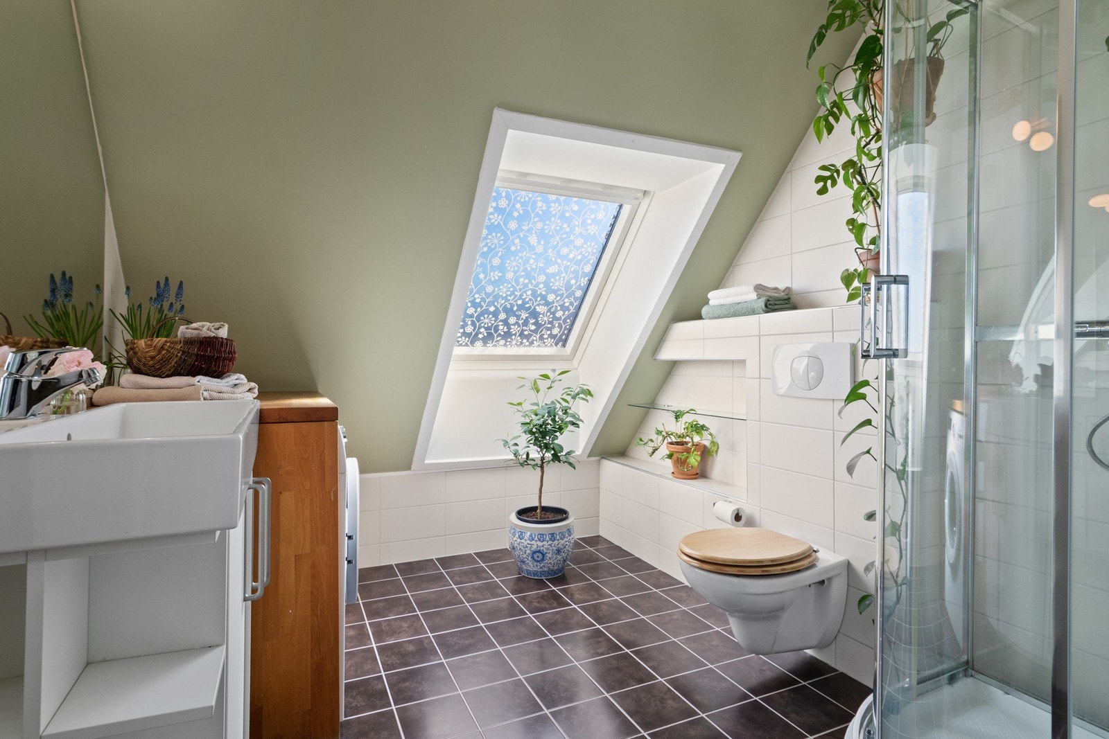 Badet fremstår som velholdt og delikat, med grønnmalte flater, delvis flissatte vegger og mørke fliser på gulv med gulvvarme. Galleribilde
