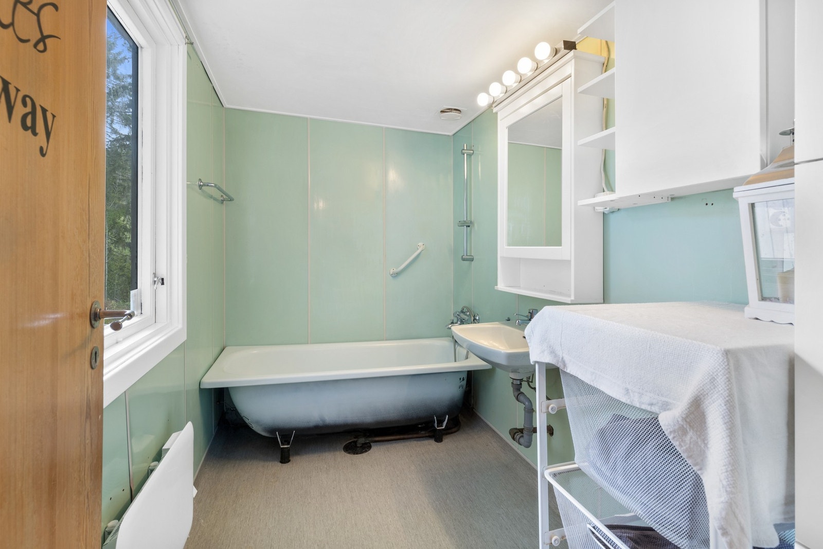 Badet har vegghengt servant, speilskap med belysning og et hvitt skap med hyller. Galleribilde