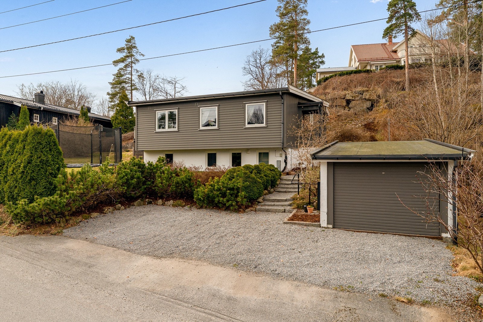 Eiendommen har en frittstående garasje med elbillader og en pent opparbeidet, gruset gårdsplass. Galleribilde