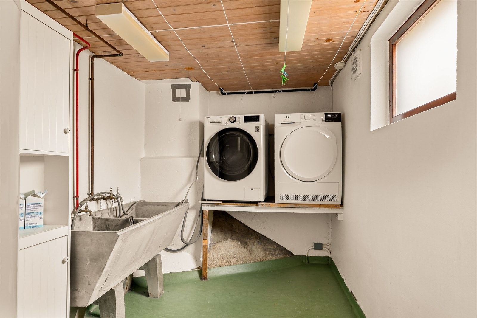 Praktisk vaskerom i kjelleren med varmekabler, opplegg for vaskemaskin og en dobbel utslagsvask. Galleribilde