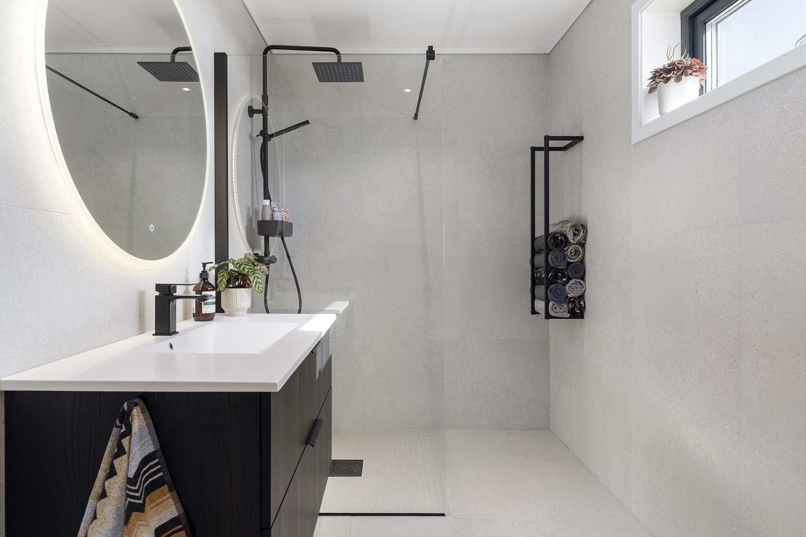 Badet er helfliset med store innbydende fliser, dusjhjørne med fine svarte detaljer og speil med sminkelys. Galleribilde